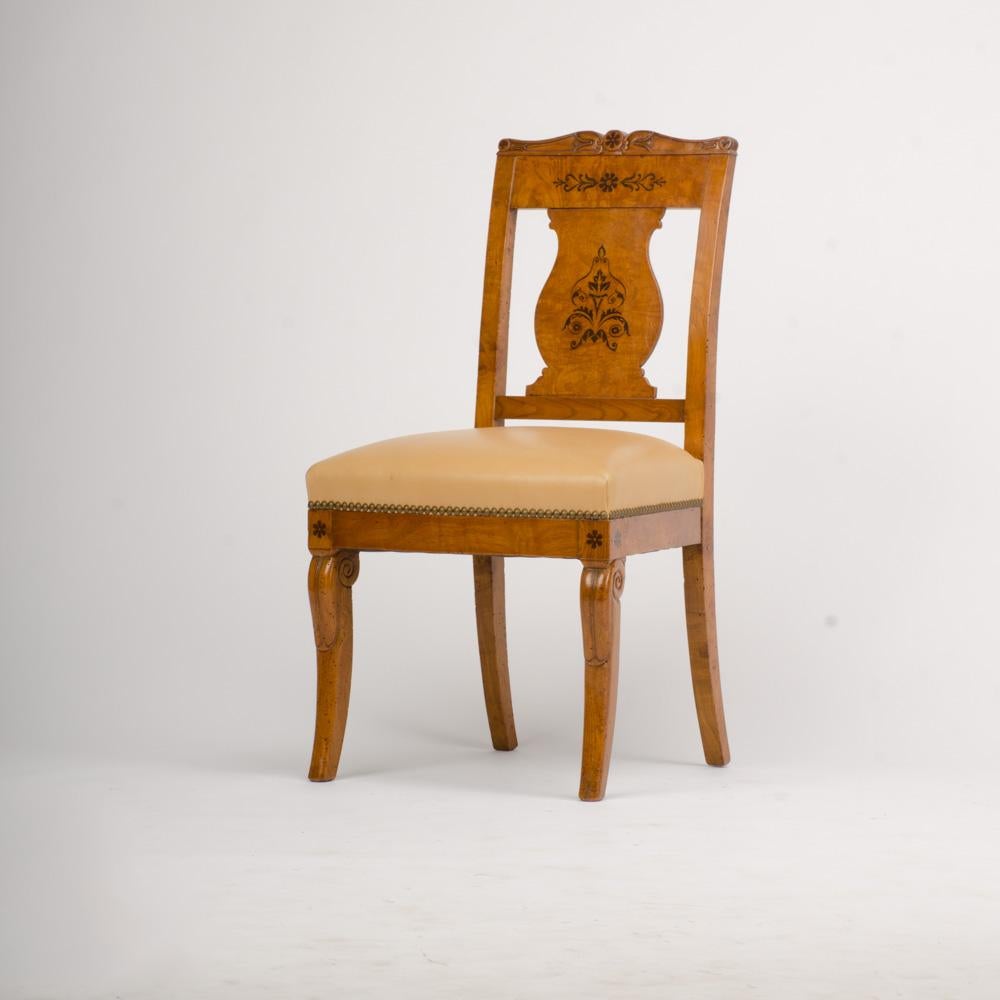 A nineteenth century burlwood framed side chair in the Biedermeier style with elegant curved and carved saber-shaped legs. Featuring ebony inlaid details on the legs and back of the chair.