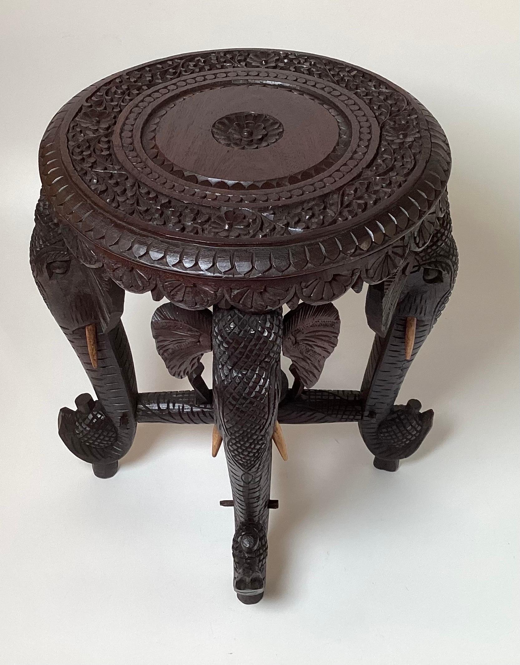 A 19th century hand carved elephant form round side table. The table is made using all pegged construction using no nails or screws the tusks are painted wood. The table stand is 18.5 inches tall, 17 inches wide, 17 inches deep at the widest point,