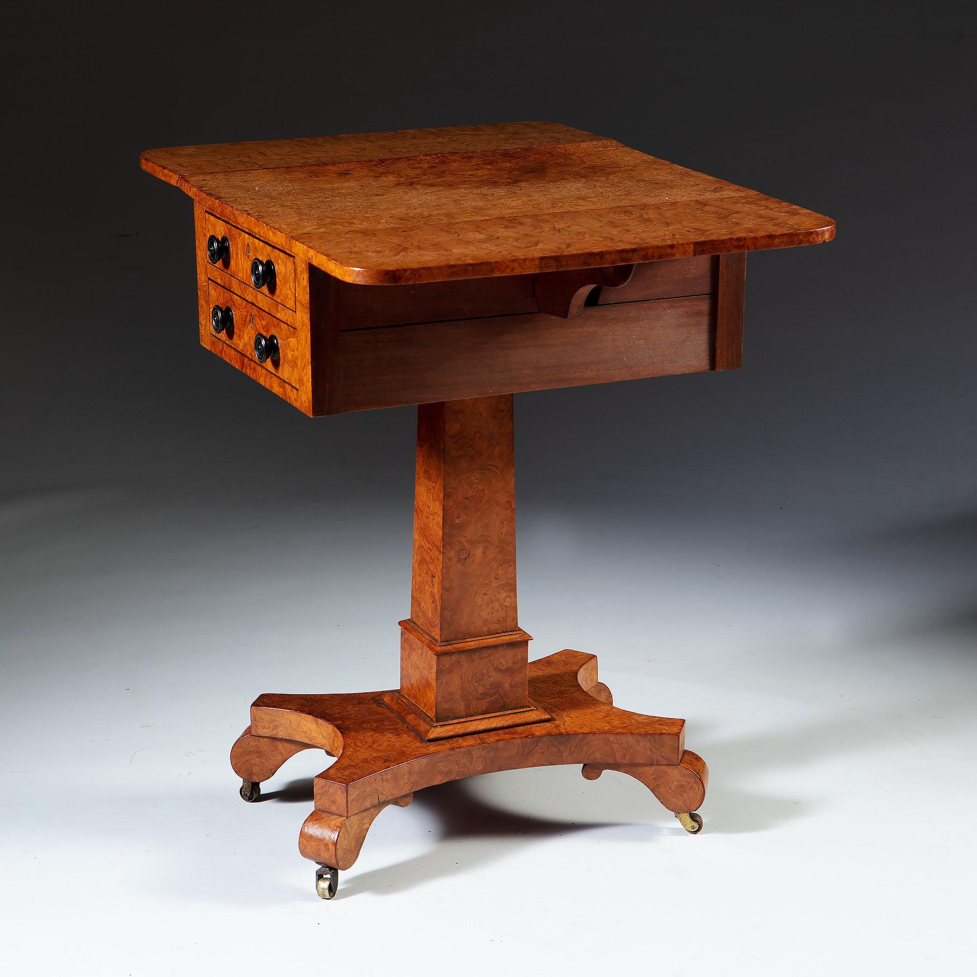 A fine 19th century burr ash work table, with drop leaf sides and two drawers to the front, the back finished with two dummy drawers to mirror the front, all supported on a quadruped base with brass castors.