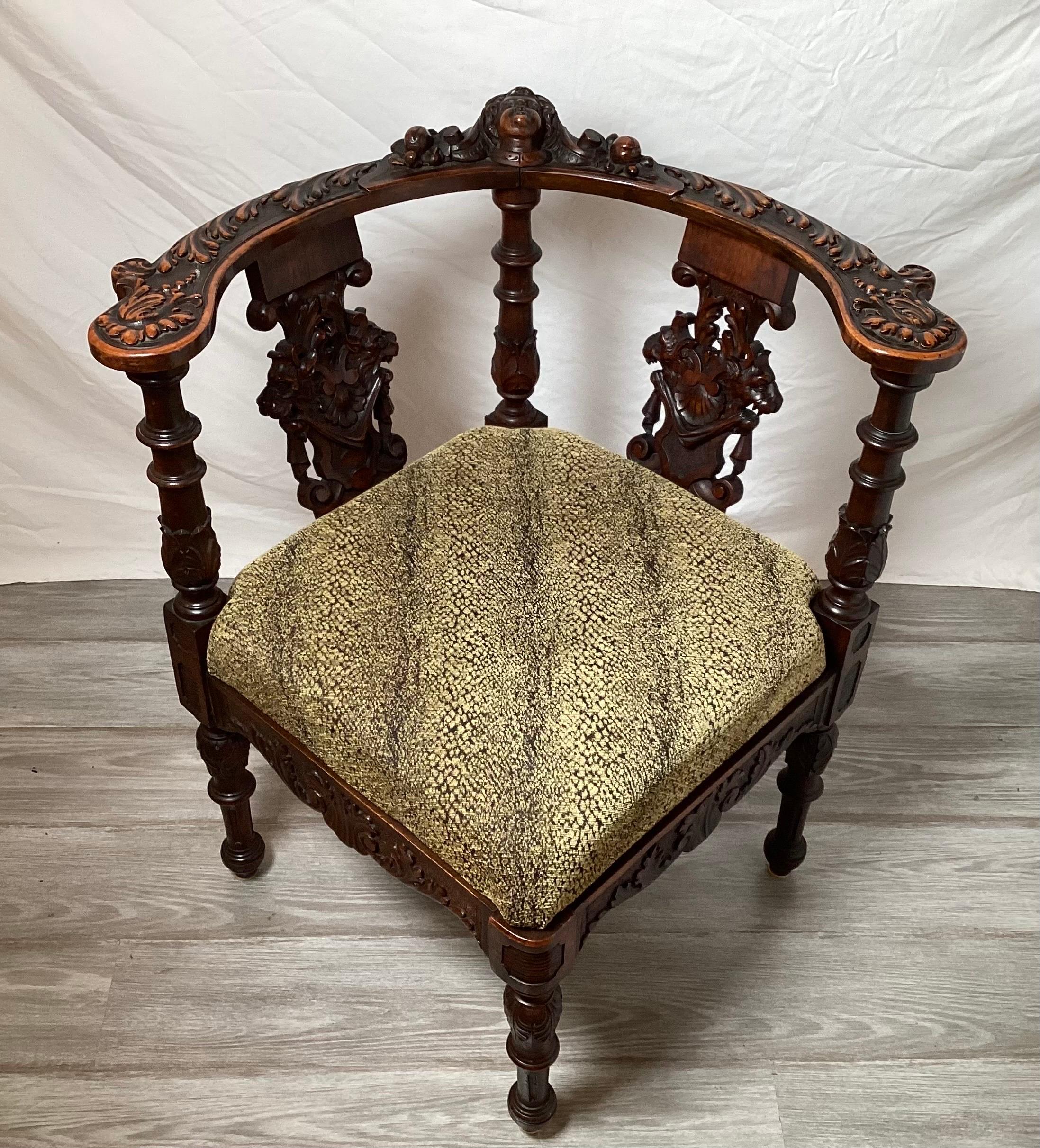 An ornately hand carved walnut corner chair, circa 1880's  The horseshoe back with carving with heavily carved splats with four turned and carved legs, the seat in an unexpected snakeskin fabric. 