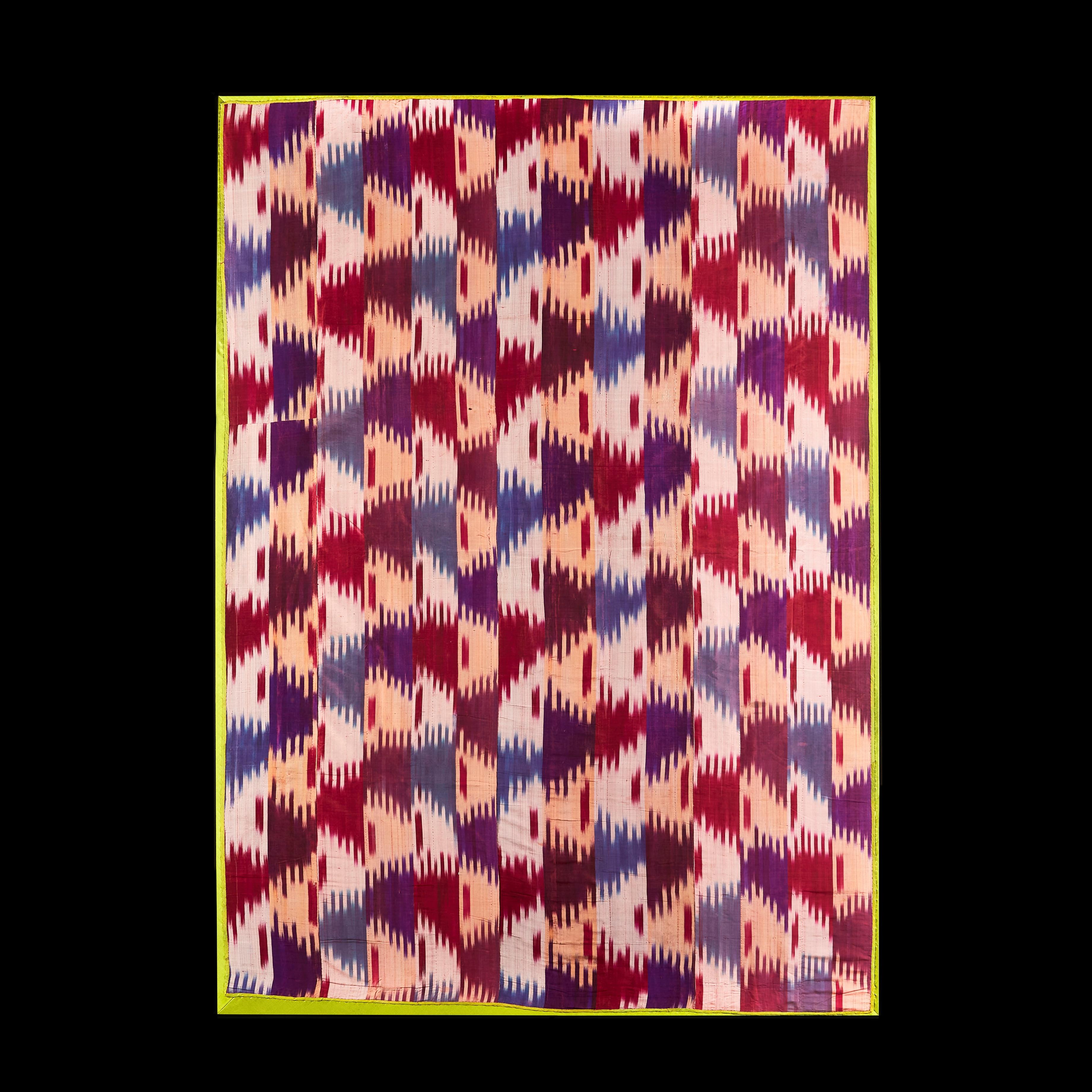 Eine große Tafel aus zentralasiatischem Ikat, verziert mit diffusen Farben in Rot, Aubergine und hellem Creme, in einem durchgehenden abstrakten Muster, eingefasst mit lindgrüner Seide, aufgespannt und jetzt montiert, auf der Rückseite gesäumt.