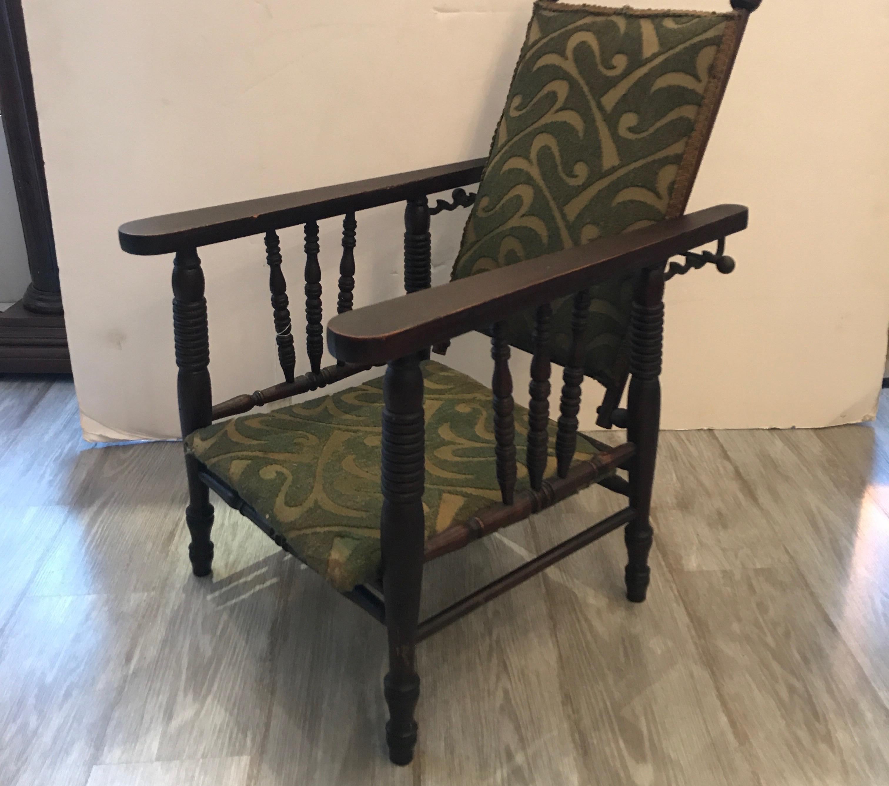 An unusual 19th century relining dark oak Childs chair. American, circa 1880. The back with an iron bar that allows the back to recline in an adjustable position. The original fabric is left on but will need recovering.