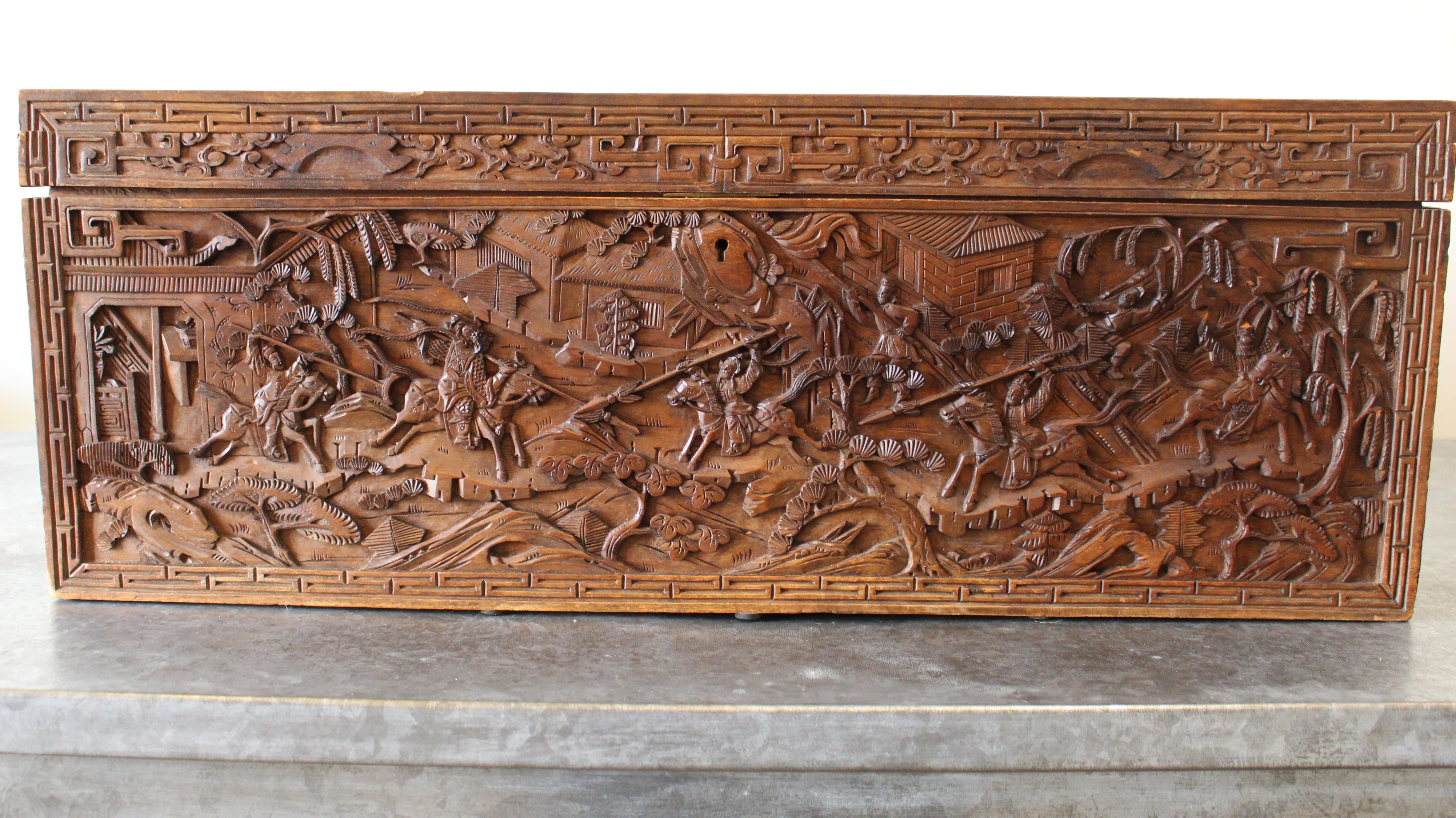 A 19th century Chinese carved camphor wood document box. The intricately carved box depicts the story of a warrior battle.  The document box showcases meticulous wooden dragon carved handles and Chinese key motifs. 