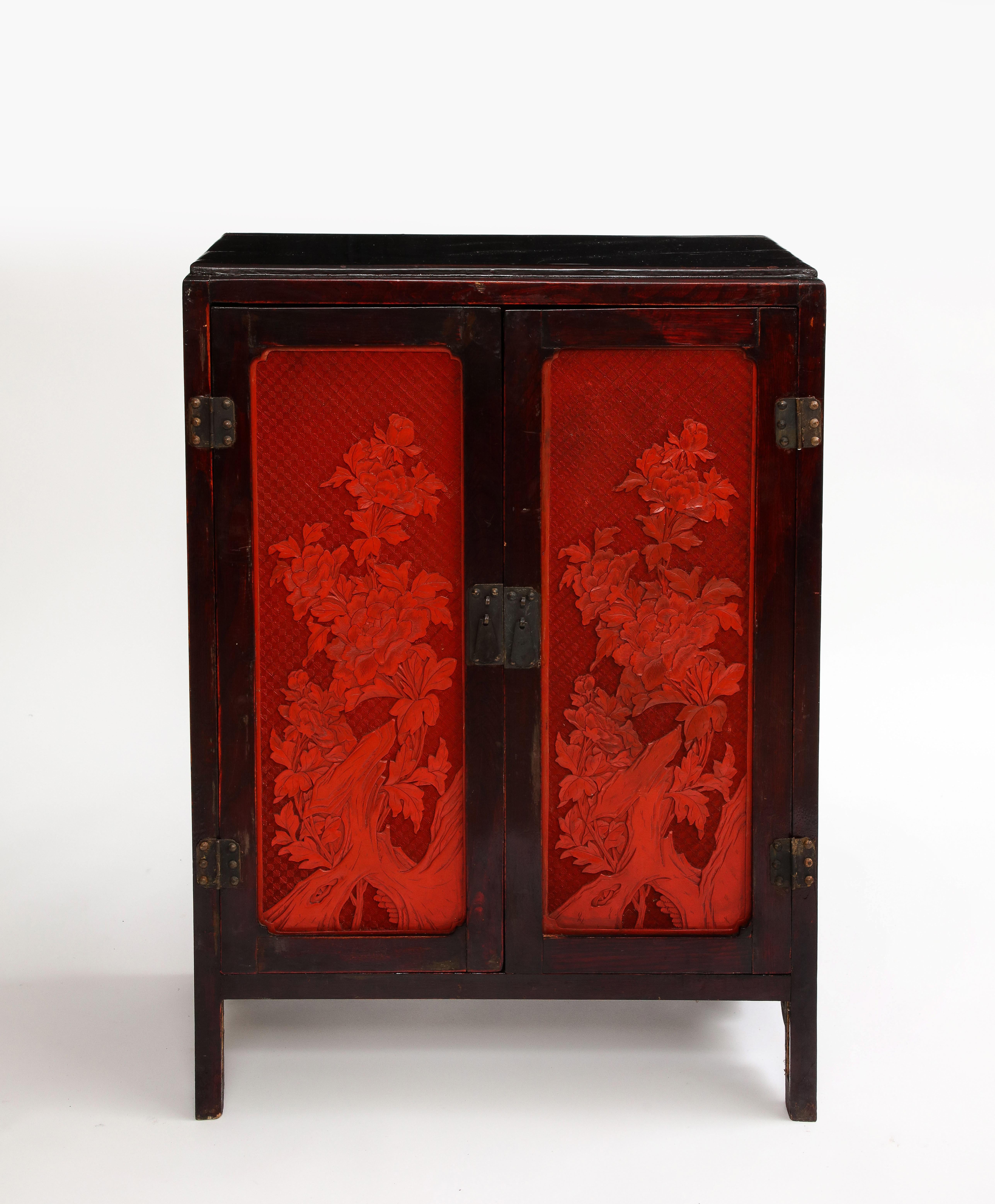 A 19th Century Chinese Cinnabar Panel Inlaid Hardwood Cabinet.  This marvelous piece showcases a harmonious fusion of artistry and craftsmanship, exuding timeless elegance and allure.  Gracing the cabinet are four meticulously crafted cinnabar