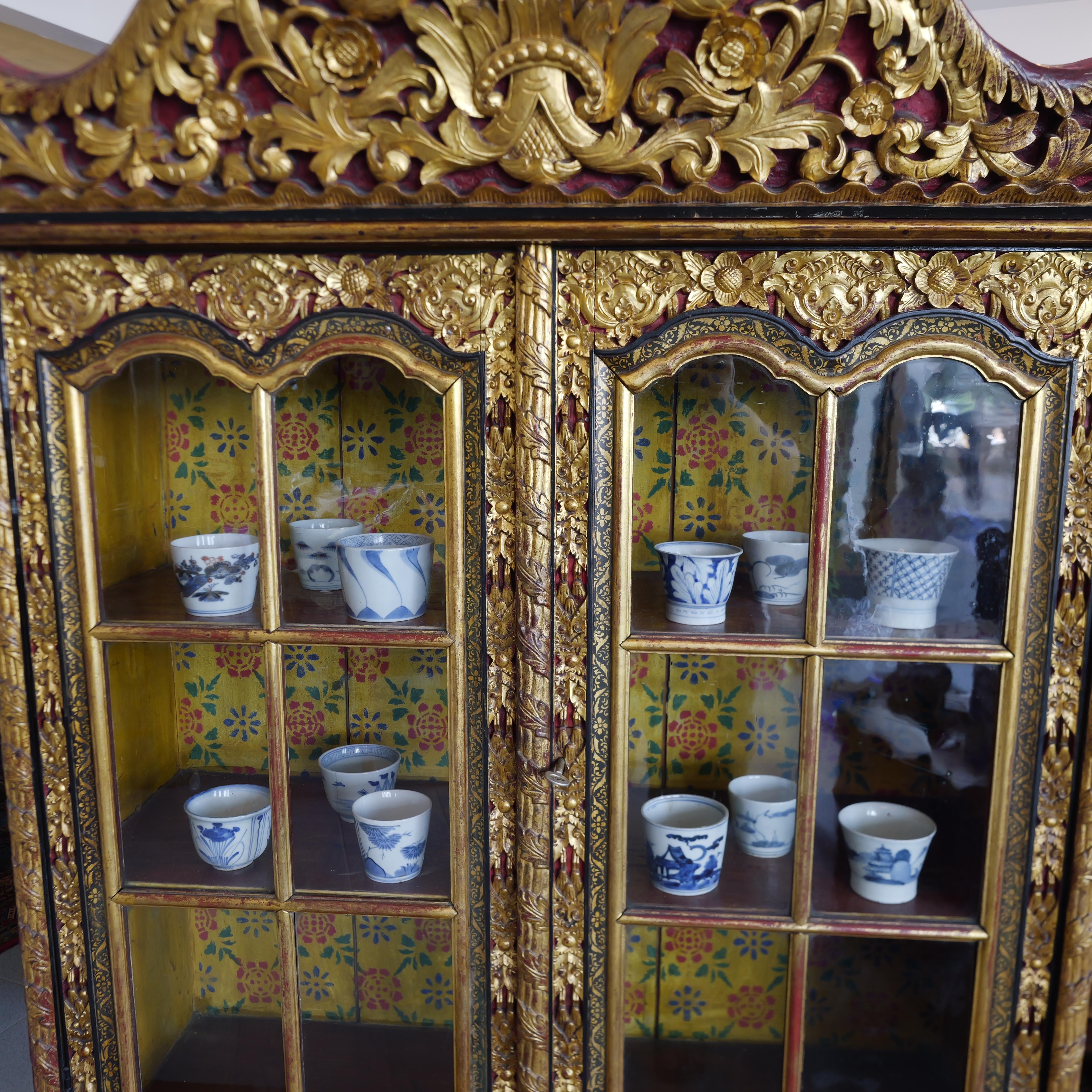 Dieser indonesische Exportschrank aus dem 19. Jahrhundert mit geschnitzter Lackfarbe und Vergoldung ist ein großartiges Beispiel für die exquisite Handwerkskunst und das künstlerische Flair des späten 19. Dieser Schrank besteht aus zwei separaten