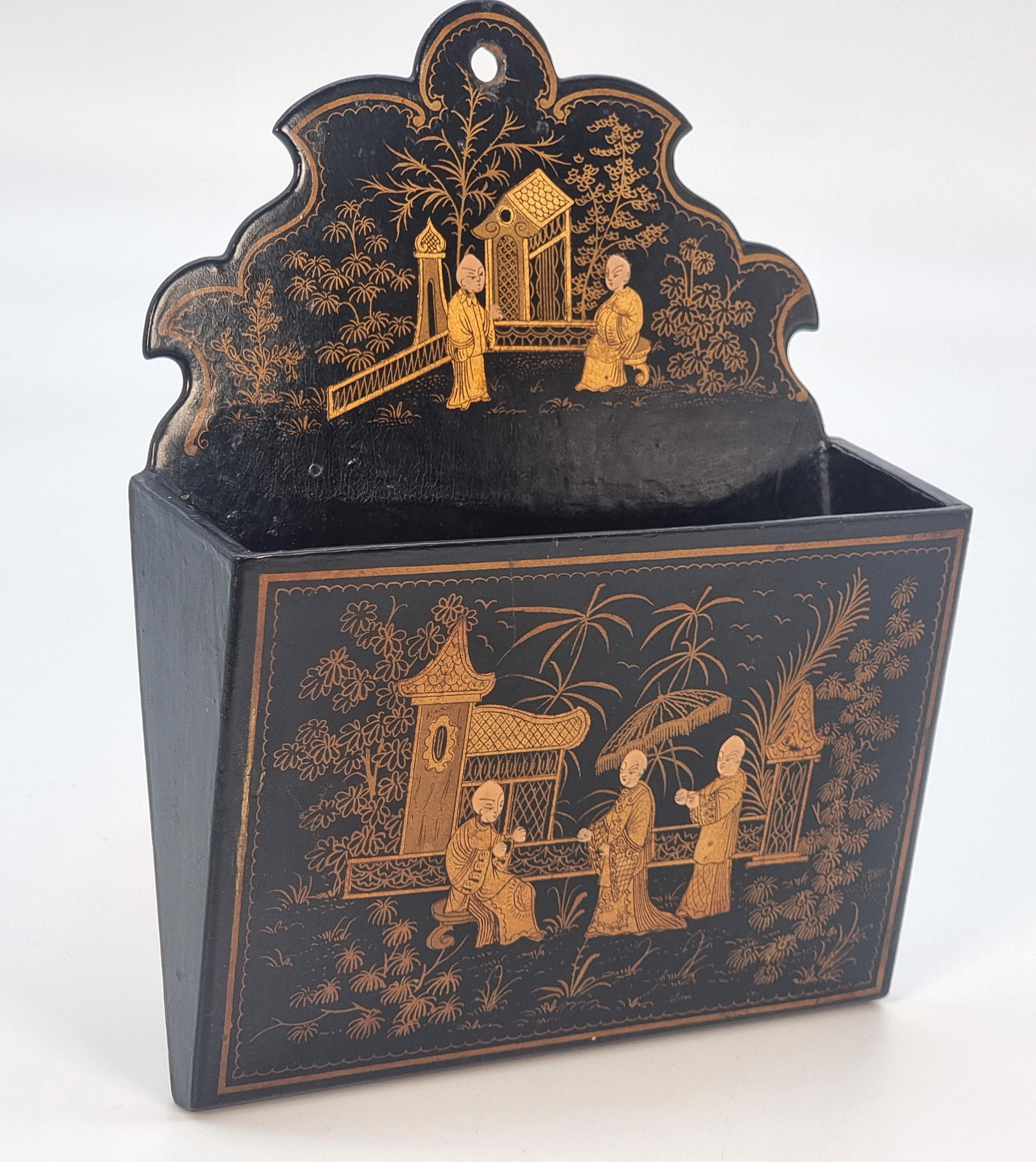 This delightful piece is in remarkably good condition. It is designed to hang on a wall to contain paper or stationary. It is made from papier mache finished with black lacquer and is beautifully hand painted in gold with a delicate chinoiserie