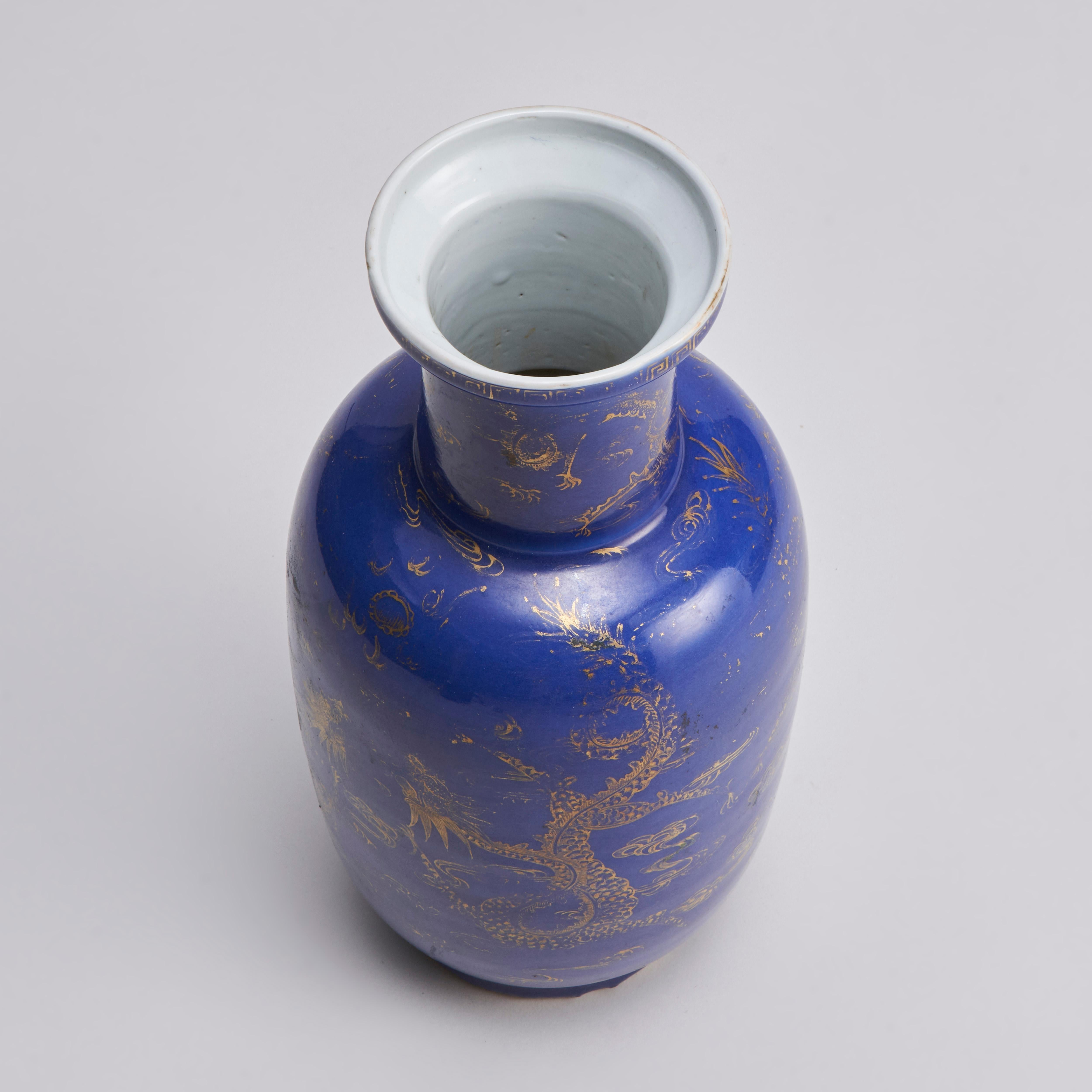 Issu de notre collection de porcelaines chinoises anciennes, ce Bangchiuping (vase Rouleau) chinois du XIXe siècle, de couleur bleu poudré, présente un élégant décor doré de dragons se déchirant dans un ciel rempli de nuages. Le col du vase est orné
