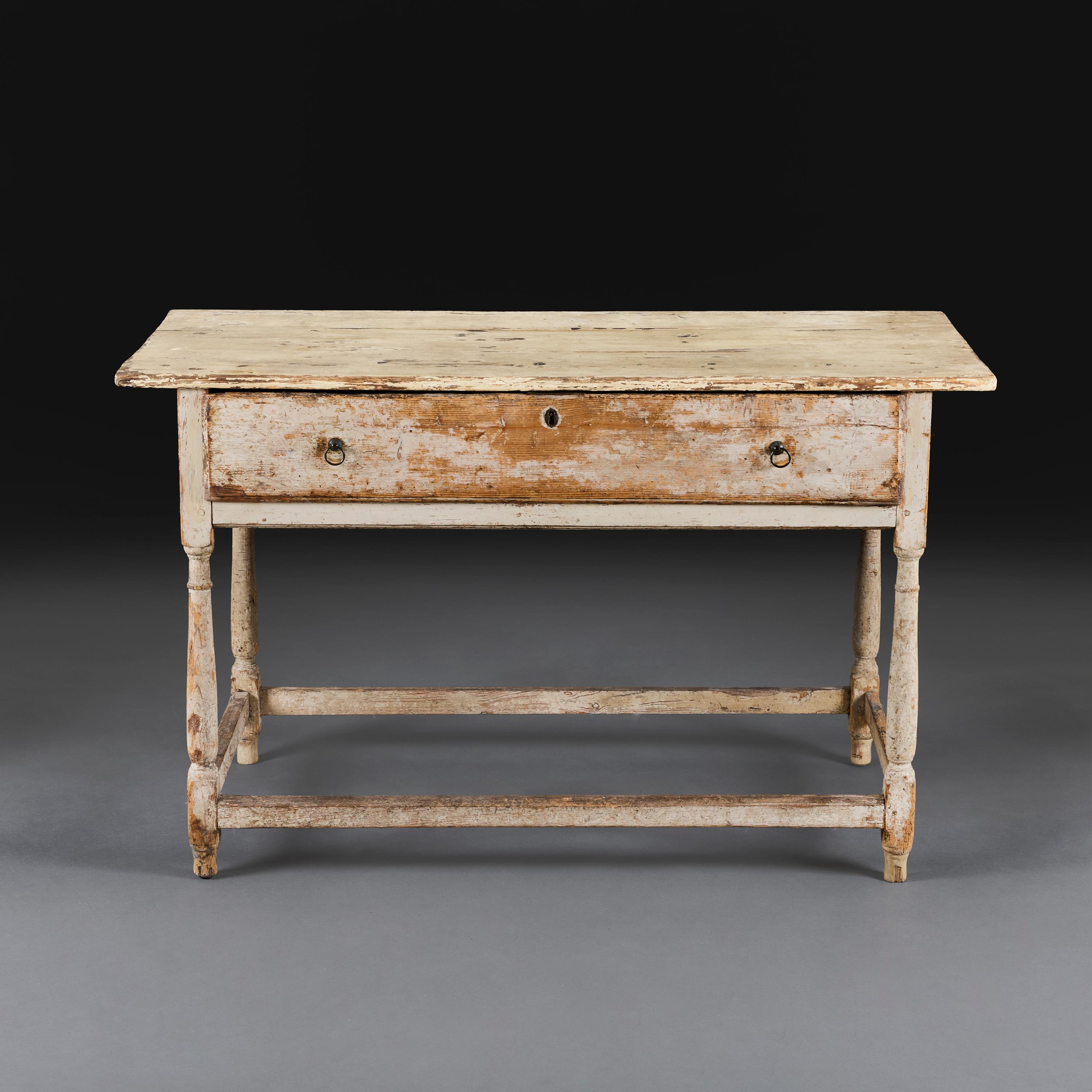 Inglaterra, hacia 1850

Mesa de salón rústica de mediados del siglo XIX, pintada de color crema, con tablero patinado y un largo cajón en el friso con asas de anilla, todo ello apoyado en cuatro patas de balaustre torneadas con cajón.

Altura 76,00