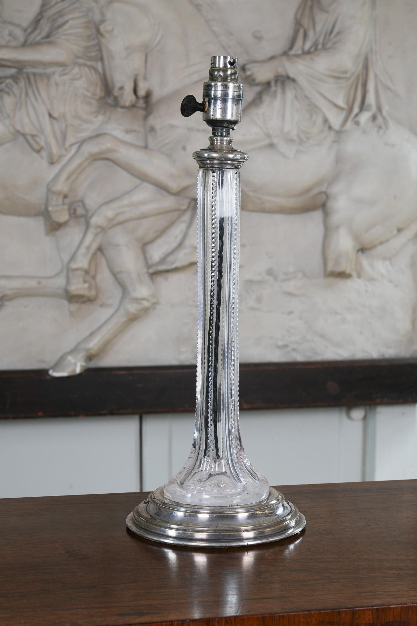A faceted and brilliant cut glass column on a circular silver plated mount.