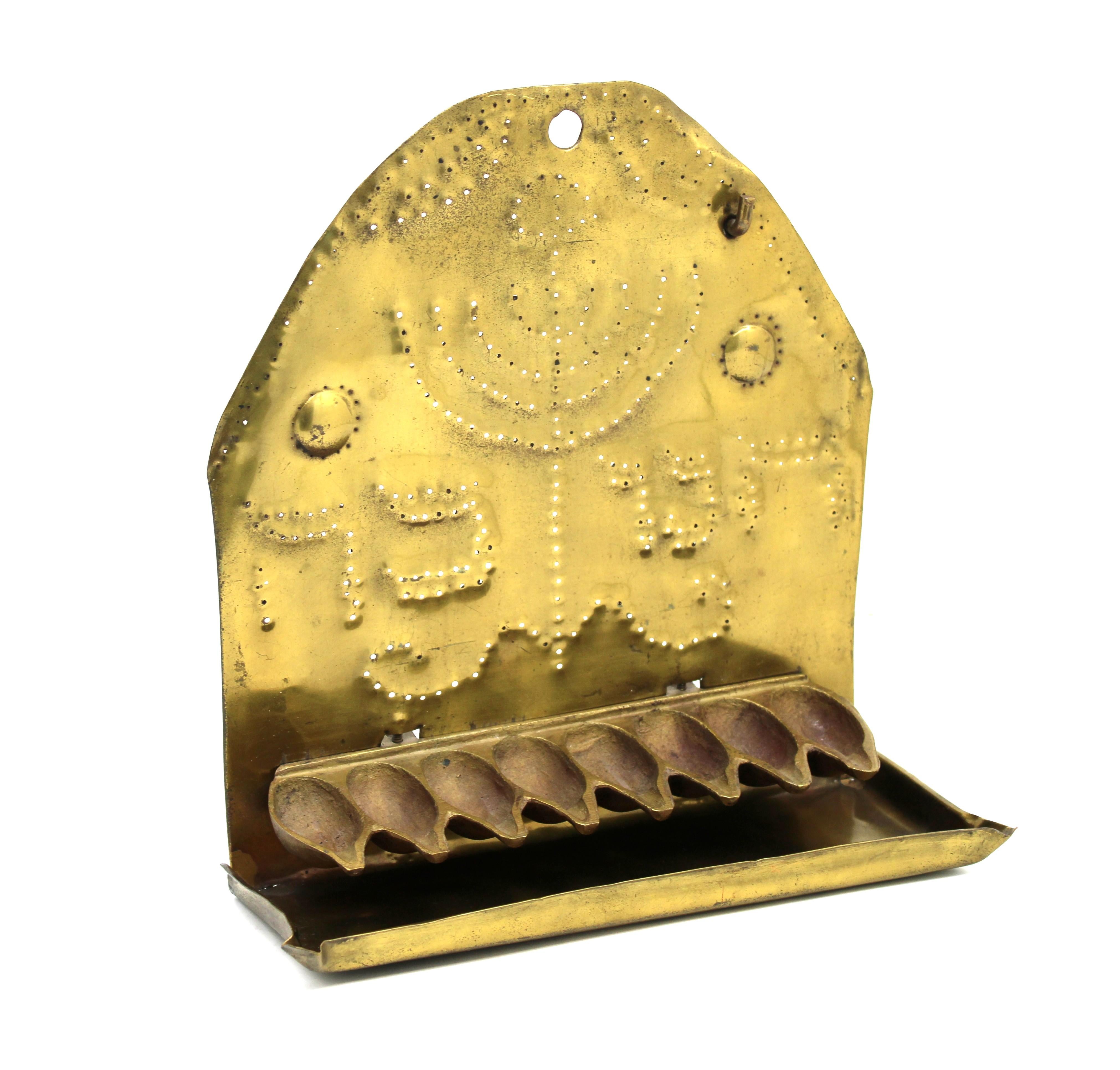 This rare and elegantly understated 19th-century Dutch brass Hanukkah lamp is crafted from a single sheet of brass, uniting both the pentagon-shaped backplate and the rectangular drip pan in one seamless form. The lamp exemplifies the refined