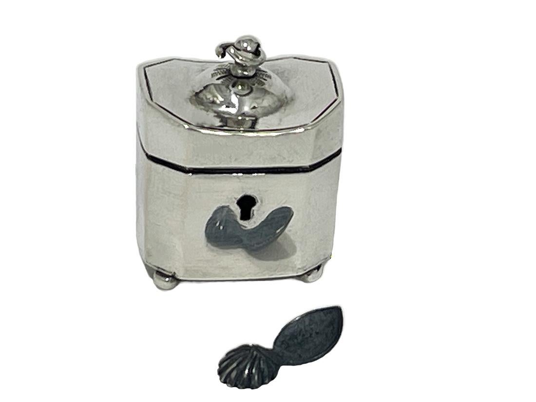 A 19th Century Dutch miniature Doll house silver tea caddy

A Dutch silver tea caddy of 2.5 cm high in octagonal shape with a thumb spoon (typical Dutch) of 1.5 cm long. The spoon made of pewter with the thumb handle in the shape of a shell. The