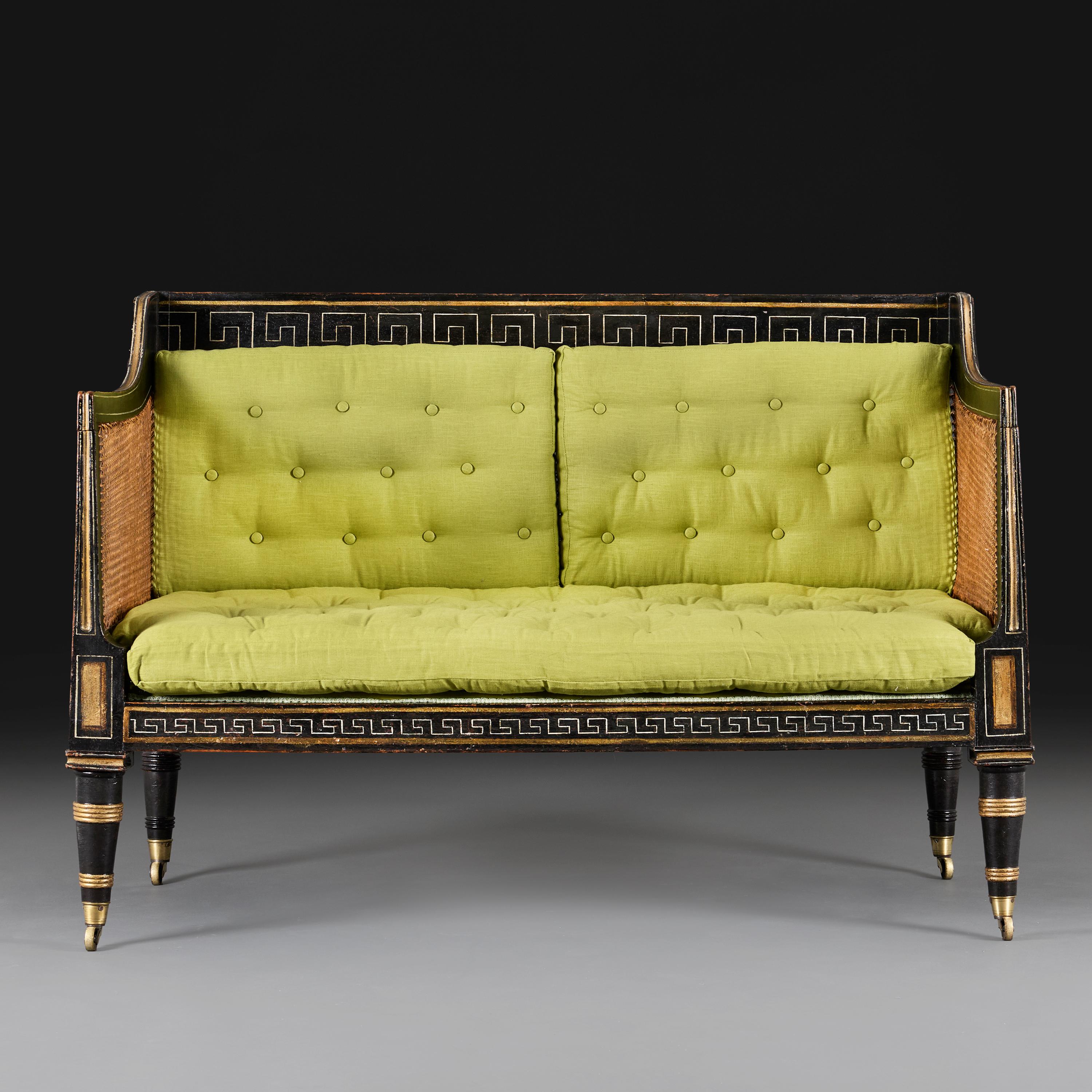 Angleterre, vers 1820

Canapé deux places en ébonite de style Regency du début du XIXe siècle, avec côtés et dossier cannelés, la traverse supérieure et la frise décorées de bordures en forme de clé grecque peintes en doré, l'assise avec des