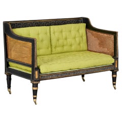 A 19th CENTURY EBONISED AND CANE REGENCY SOFA
