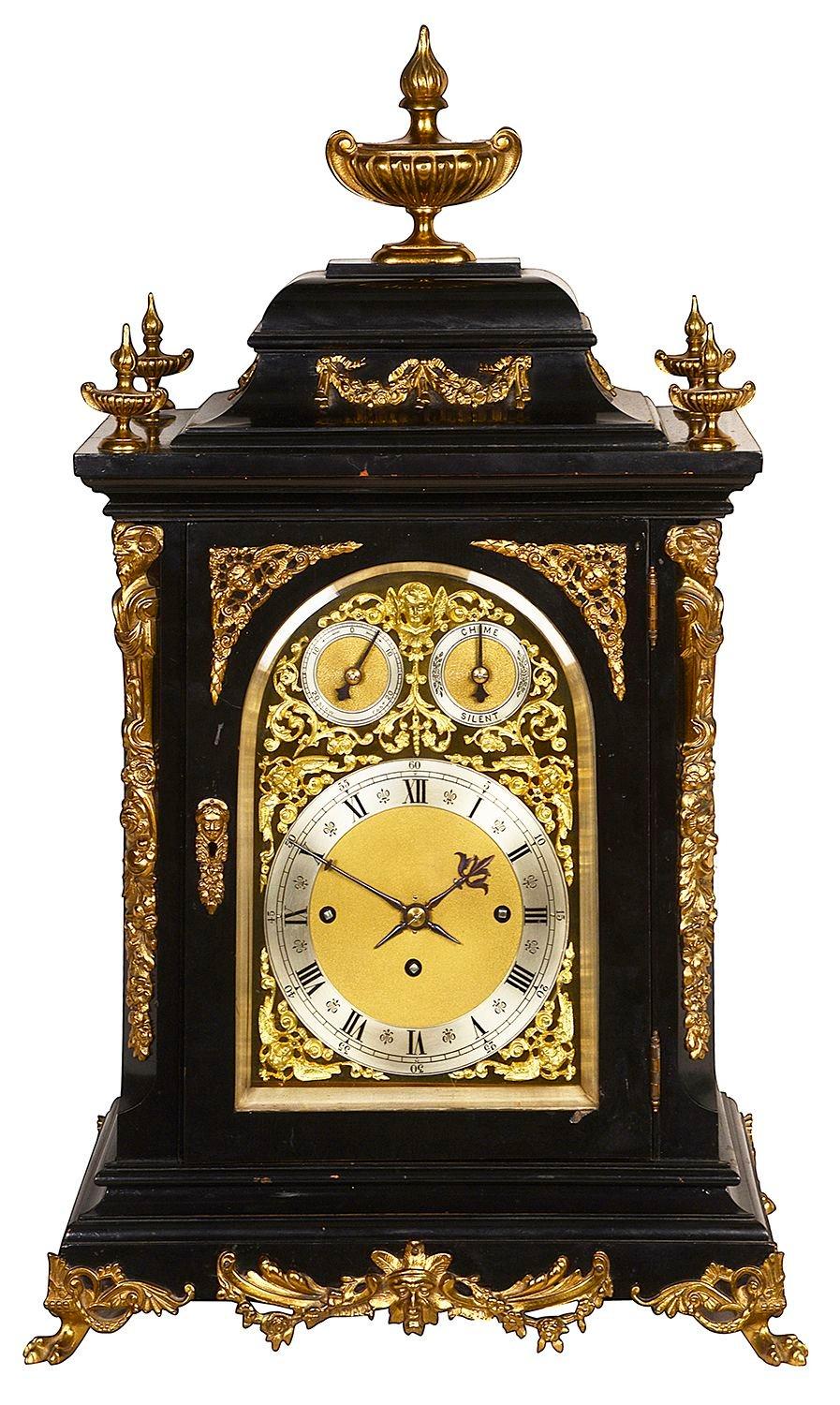An imposing 19th century ebonised, Westminster chiming mantle / bracket clock, having classical gilded ormolu urn finials and scrolling foliate mounts. An arched brass dial with a three train, eight day movement, with a strike / silent dial and