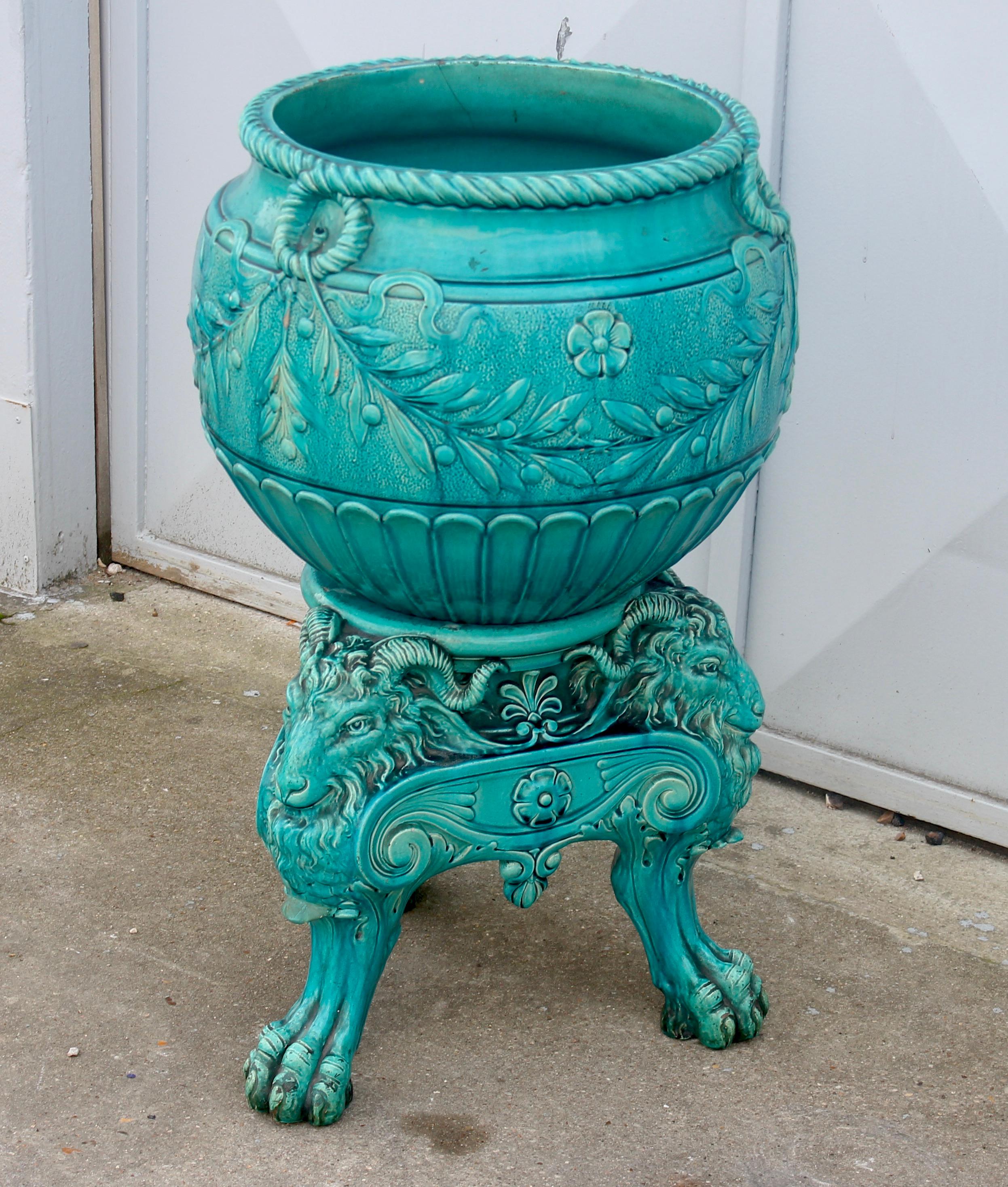 A 19th century England Burmantofts Pottery turquoise blue Faïence jardinière and stand set
cachepot in earthenware with blue-turquoise glaze decorated with a frieze of laurels and godrons. 
It rests on its tripod pedestal with heads and claws of