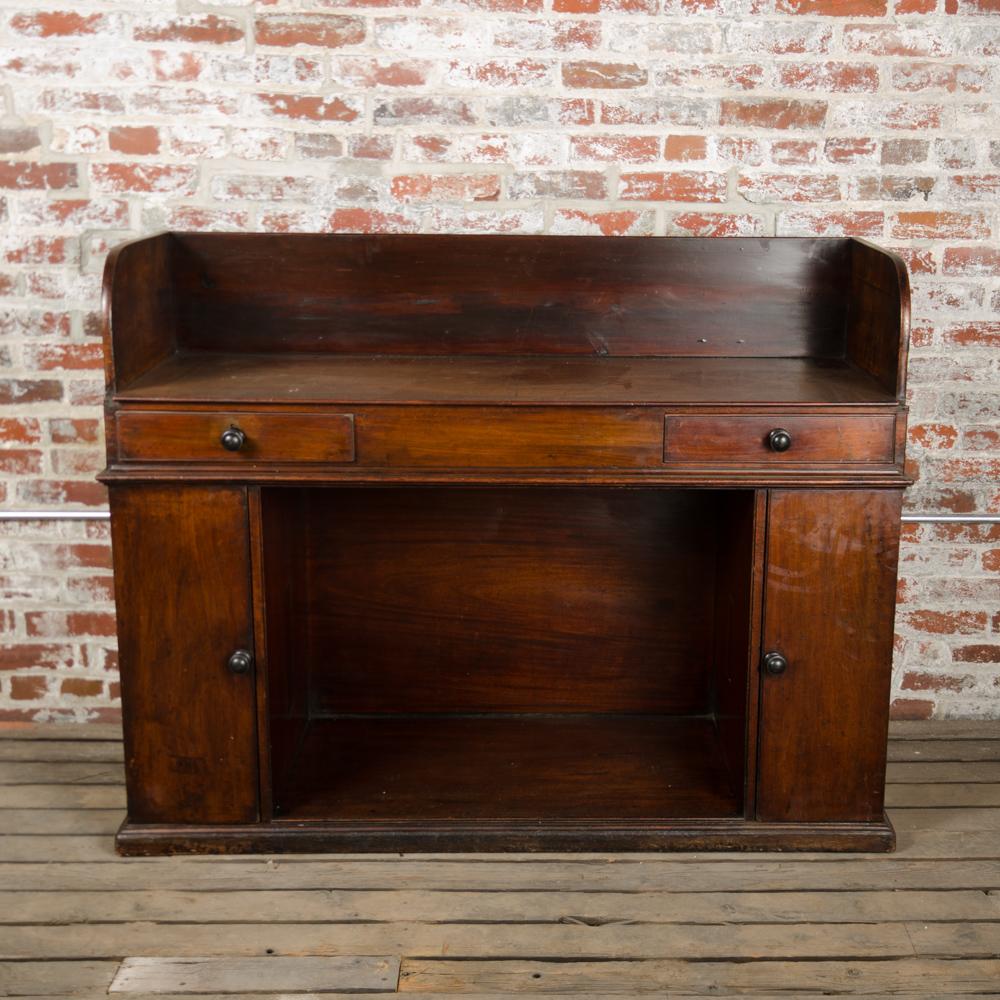 A nineteenth century English mahogany kneehole desk. Two drawers and kneehole flanked by two mahogany panel doors opening to reveal shelves inside.
 