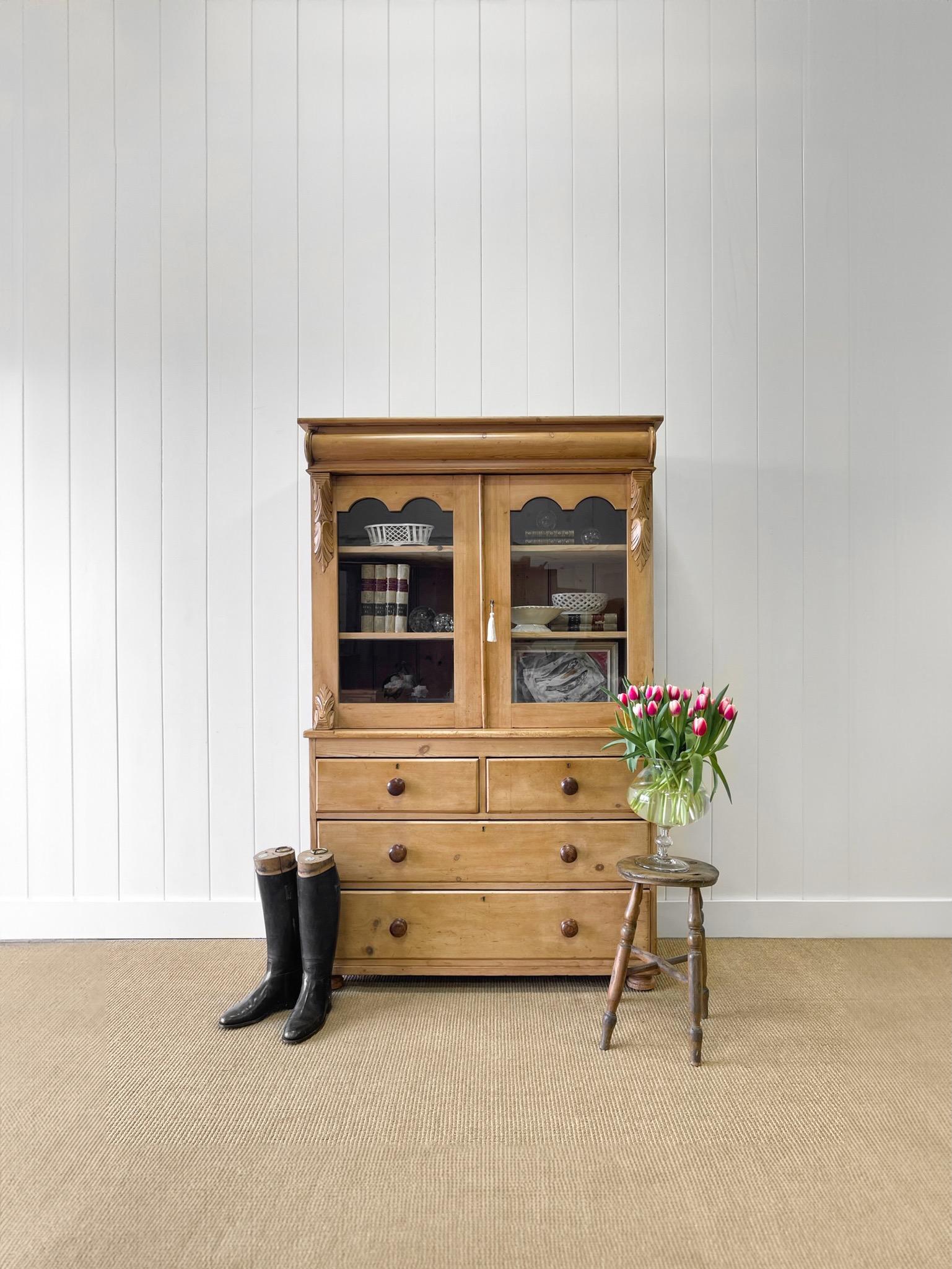 A lovely antique English pine bookcase cabinet or hutch.  The top portion of this piece has 2 glass doors that open to reveal ample shelving.  The lower cupboard has four drawers for additional storage space.  This is a very elegant and pleasing