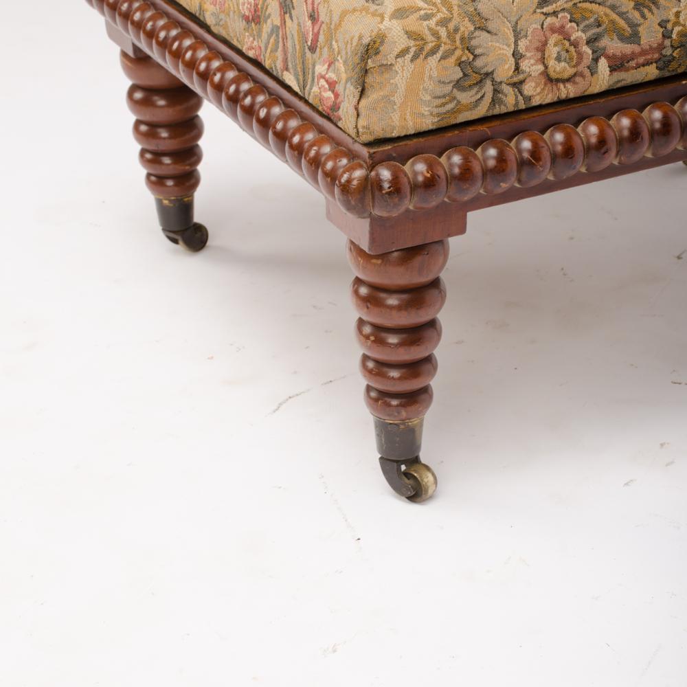 A 19th Century English spool chair, carved in mahogany and covered with floral tapestry upholstery.