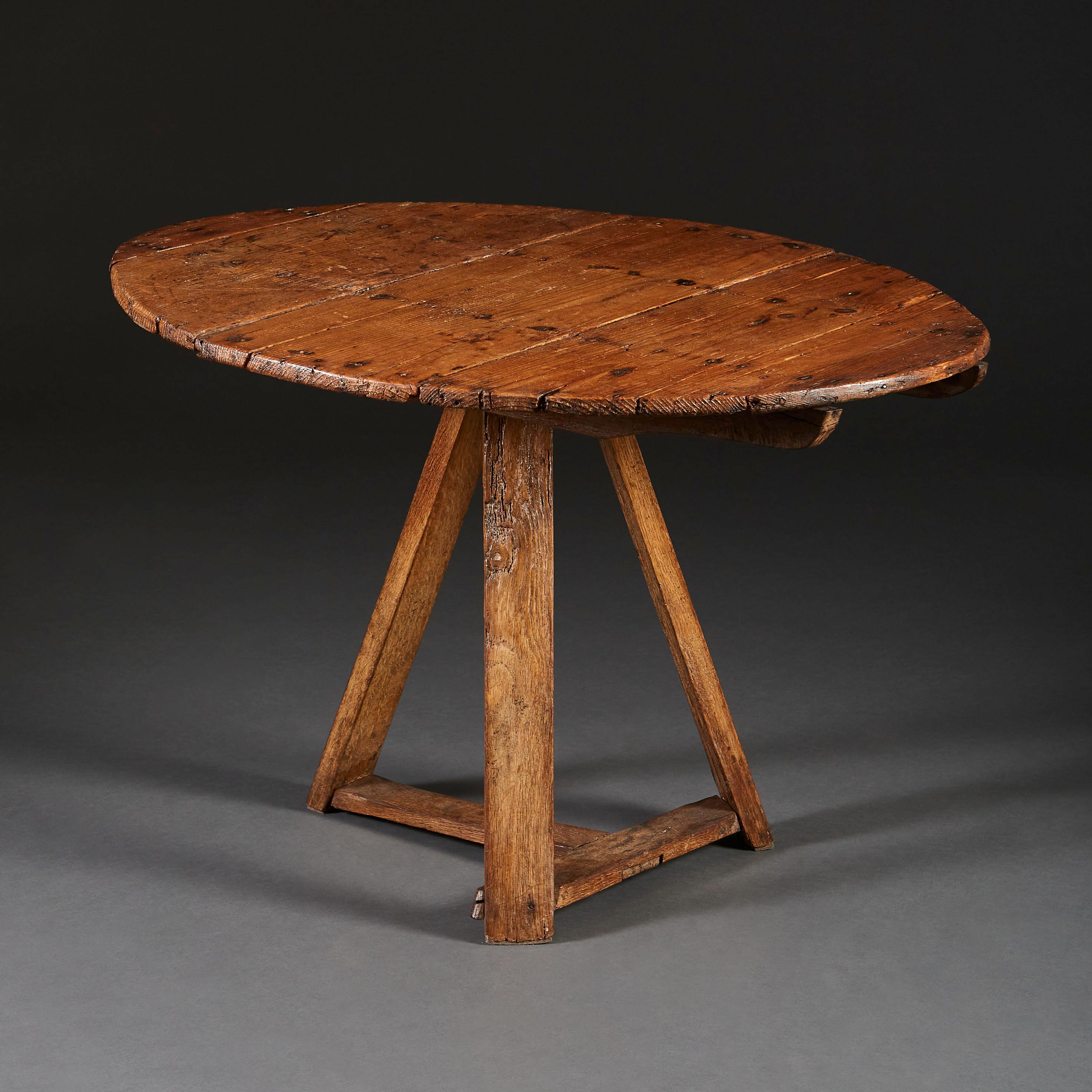 A mid nineteenth century English vernacular pine table, with tripod frame base, the oval tilt top with a peg to the underside of the table.