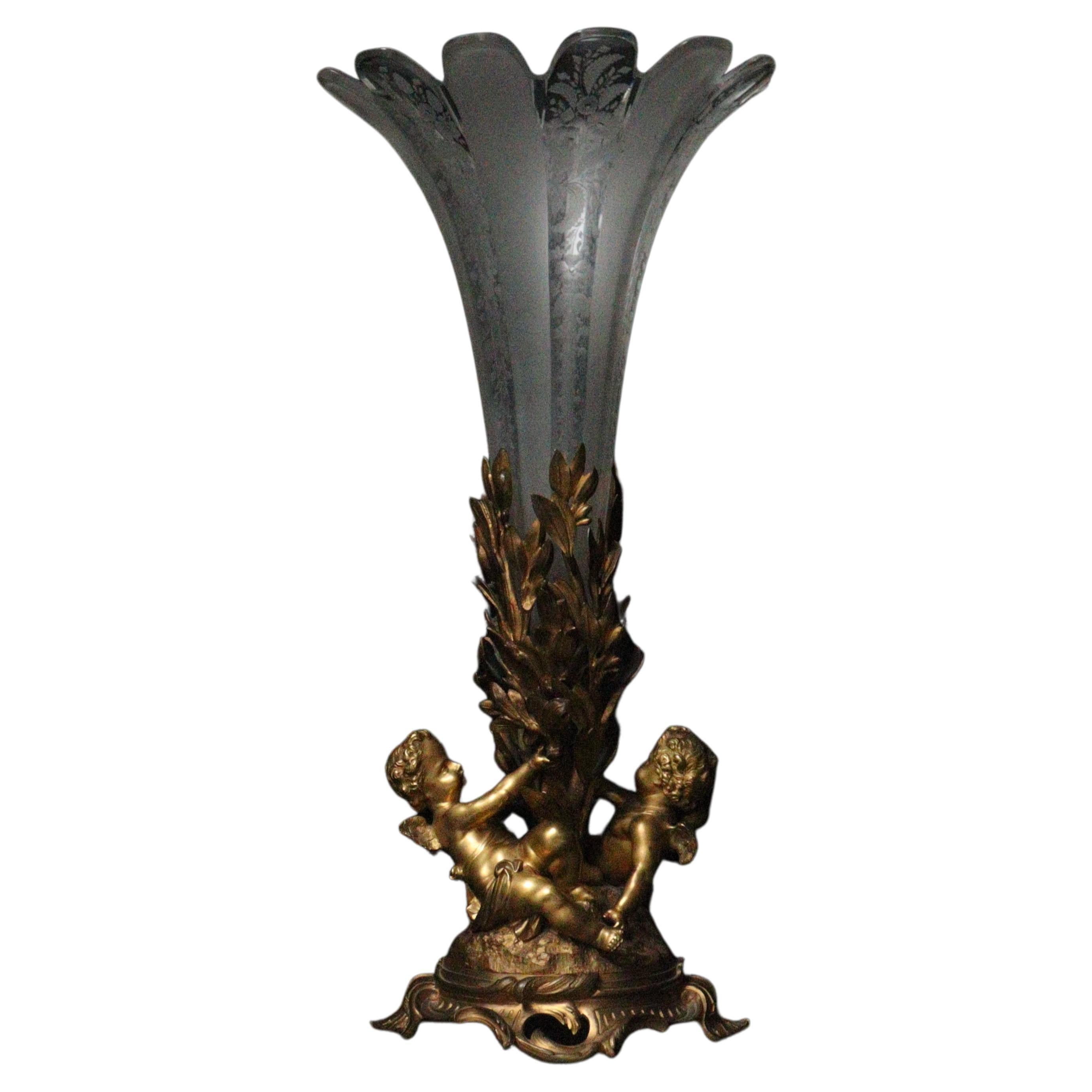 A French 19th century Baccarat crystal and ormolu cornet vase centerpiece.

The gilt bronze base decorated with two cupids from which laurel leaves emerge forming a receptacle for the Baccarat crystal cornet with frosted decoration and engraved