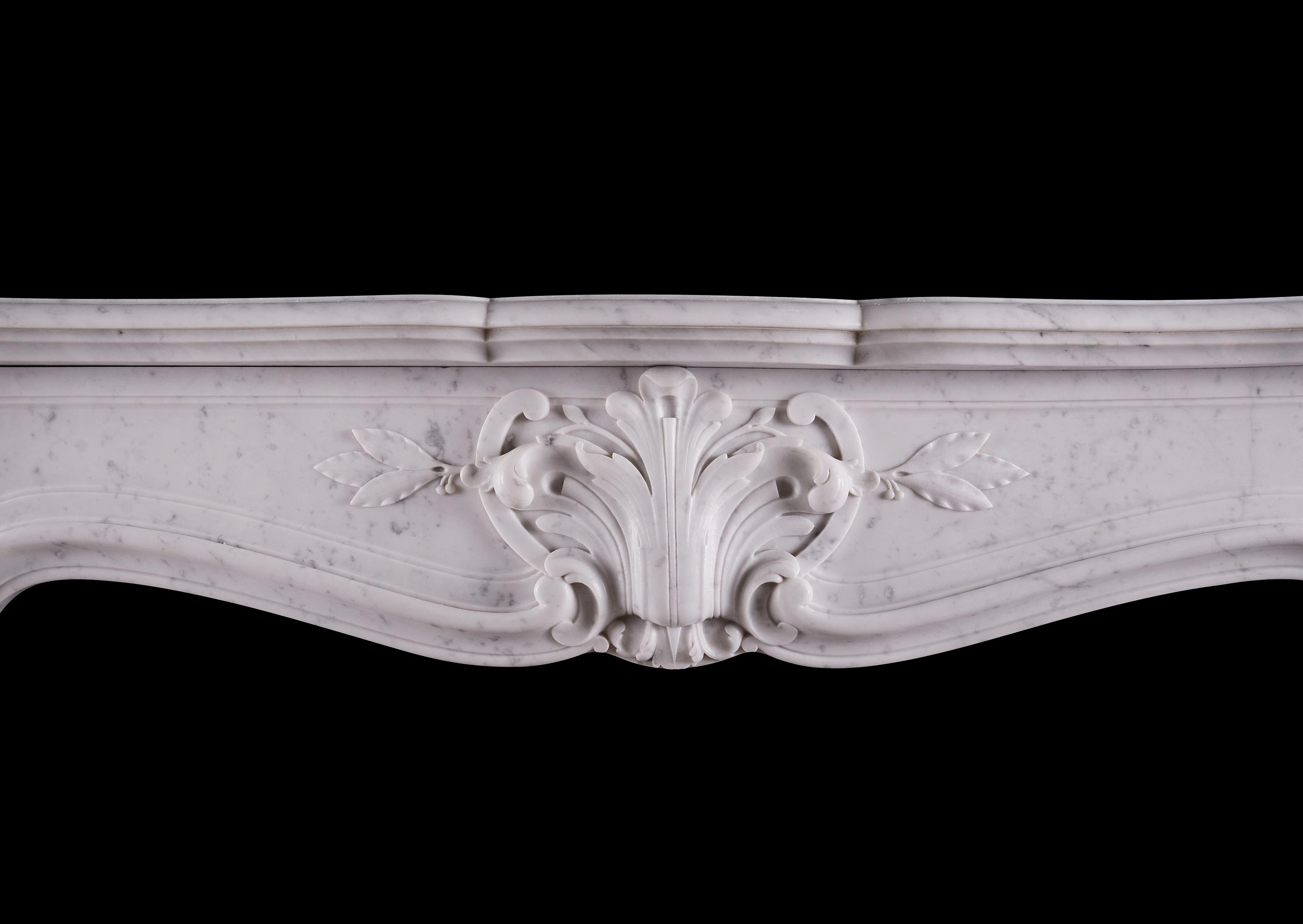 Ein französischer Kamin aus Carrara-Marmor aus dem 19. Jahrhundert im Louis-XV-Stil. Die geformten, kannelierten Pfosten werden von Paneelen und Rankenwerk gekrönt, darüber befinden sich geschnitzte Blätter. Der geformte Fries mit geschnitzter