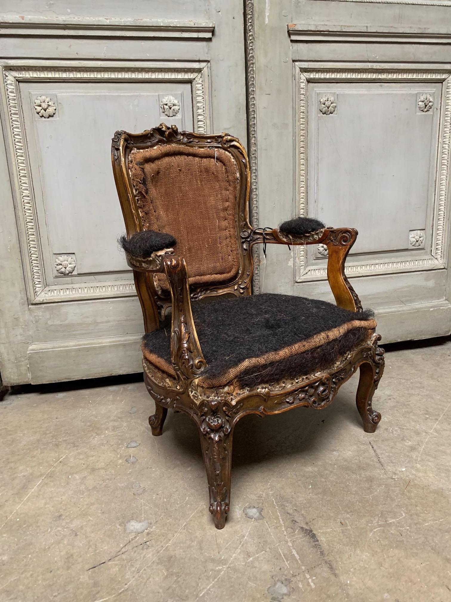 This charming 19th century French Louis XV style diminutive child's armchair features a sculptural giltwood fame carved with scrolls, leaf work and rosettes.
The fauteuil has the original upholstery padding and horsehair.