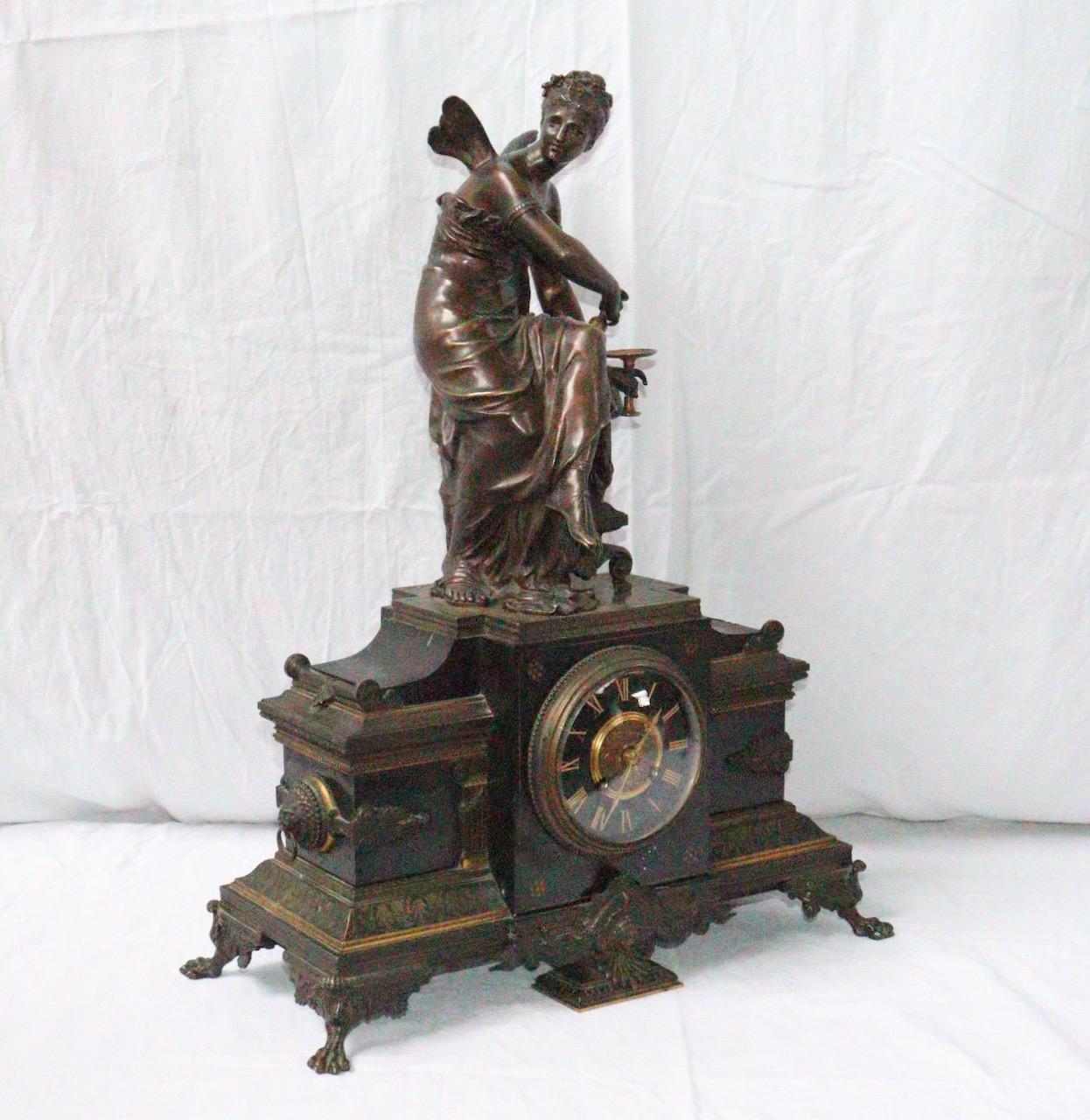 A 19th century French neoclassical clock 

The Mantelpiece with a winged woman figure in brown patina and ormolu resting on a black marble base , the clock with central projection with a dial with Arabic numerals.
The side adorned with Lion's