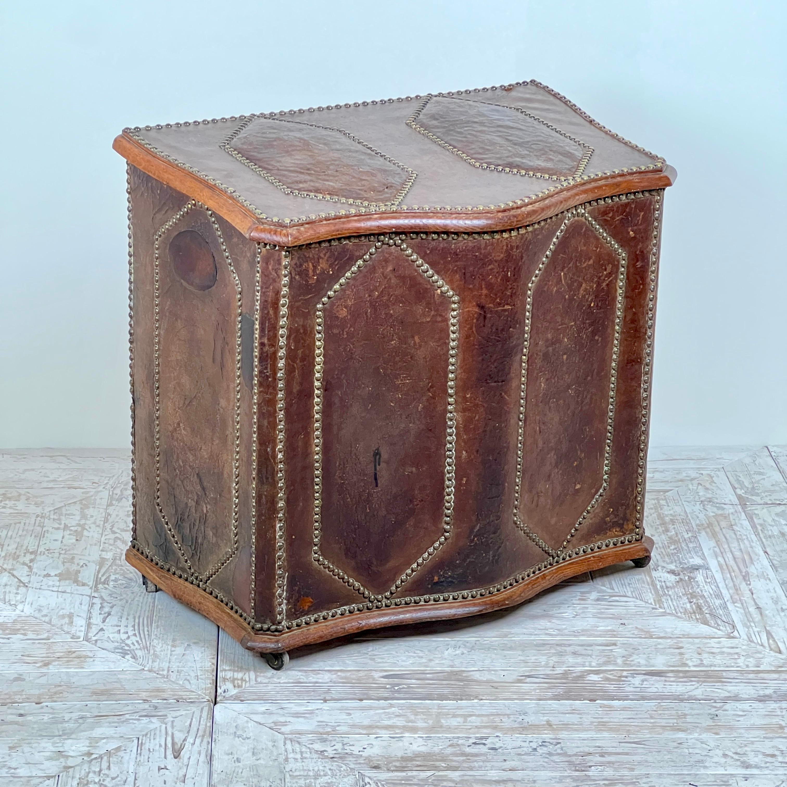 Un'affascinante cassetta di legno o contenitore in pelle e Oak francese del XIX secolo. Di forma serpentina con decorazione geometrica a losanghe sul coperchio e sulla base. Rivestita in pelle con attraenti dettagli di borchie. Si regge su rotelle
