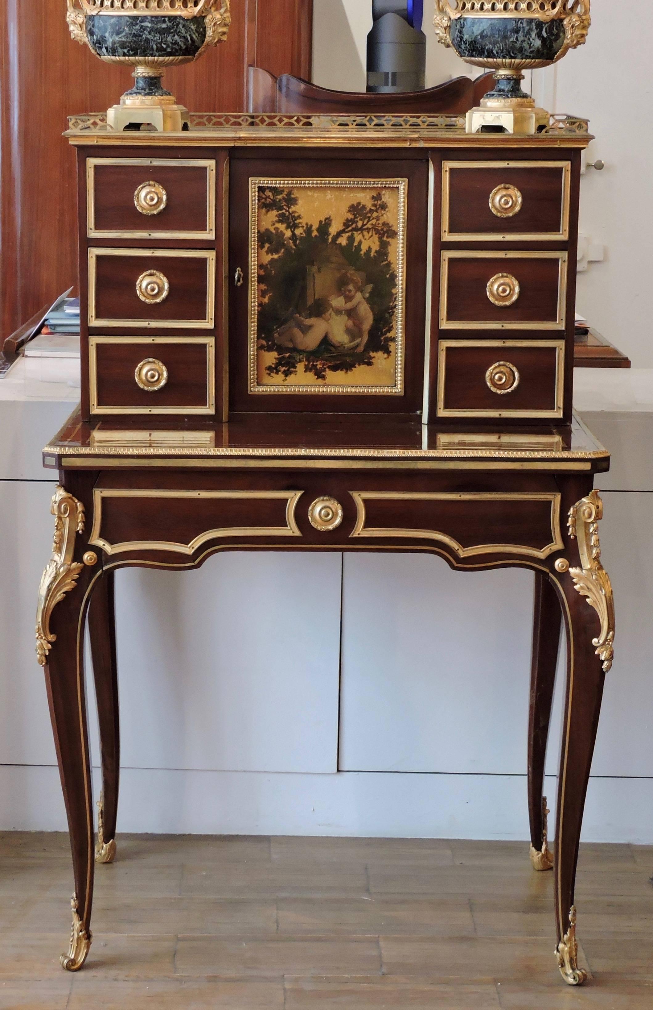 A 19th century French ormolu-mounted mahogany and Vernis Martin Bonheur du Jour
The upper structure with central door with two Putti design Vernis Martin Panel flanked by six Drawers surmounted by a Red Griotte marble top, over writing surface and