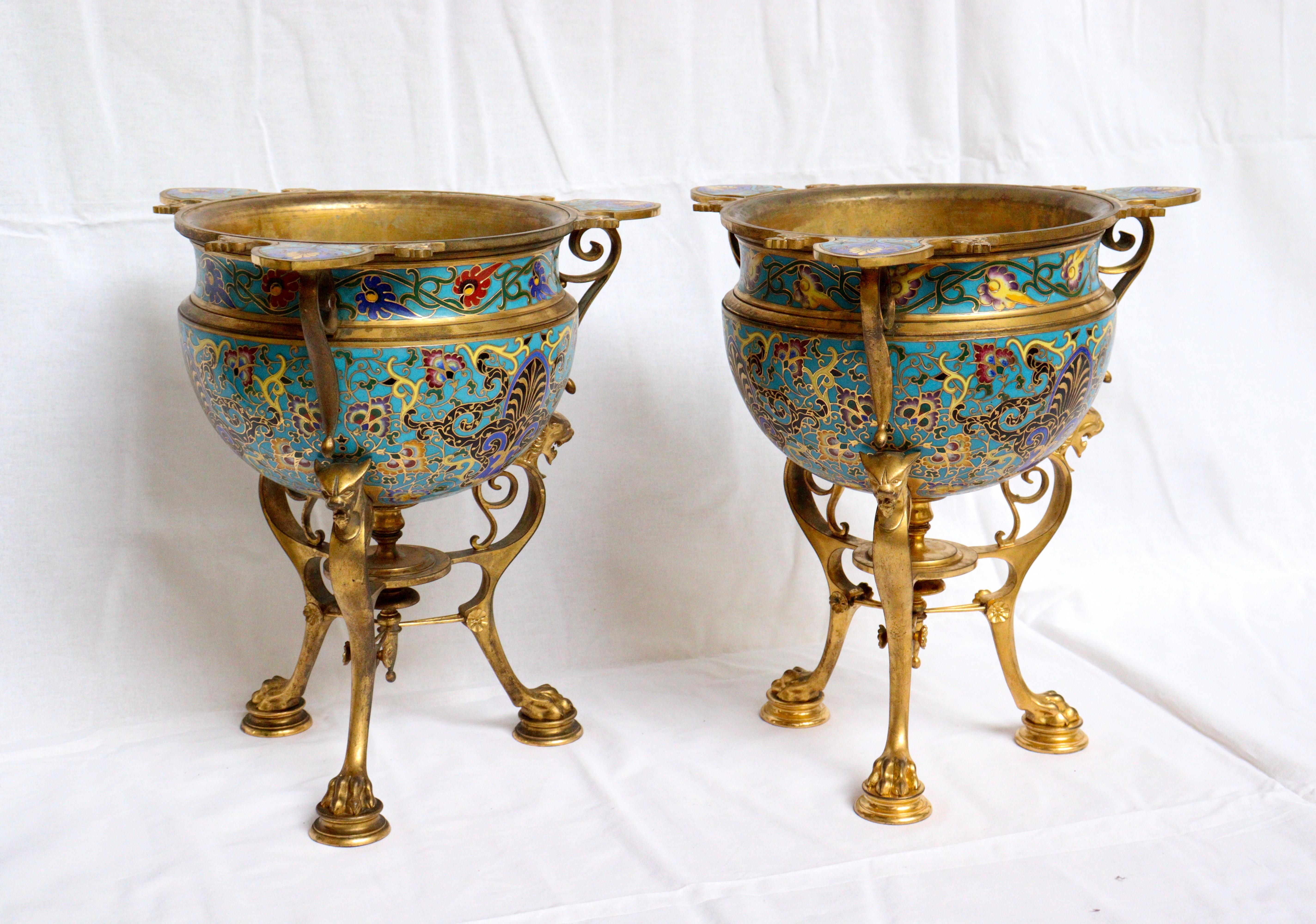 A 19th century French Ormolu and Cloisonne enamel pair of jardinieres “En Athéniennes” 
The central bowl with three scrolling handles and supported on a tripod stretchered base formed as three panther monopodia terminating in claw feet, the body