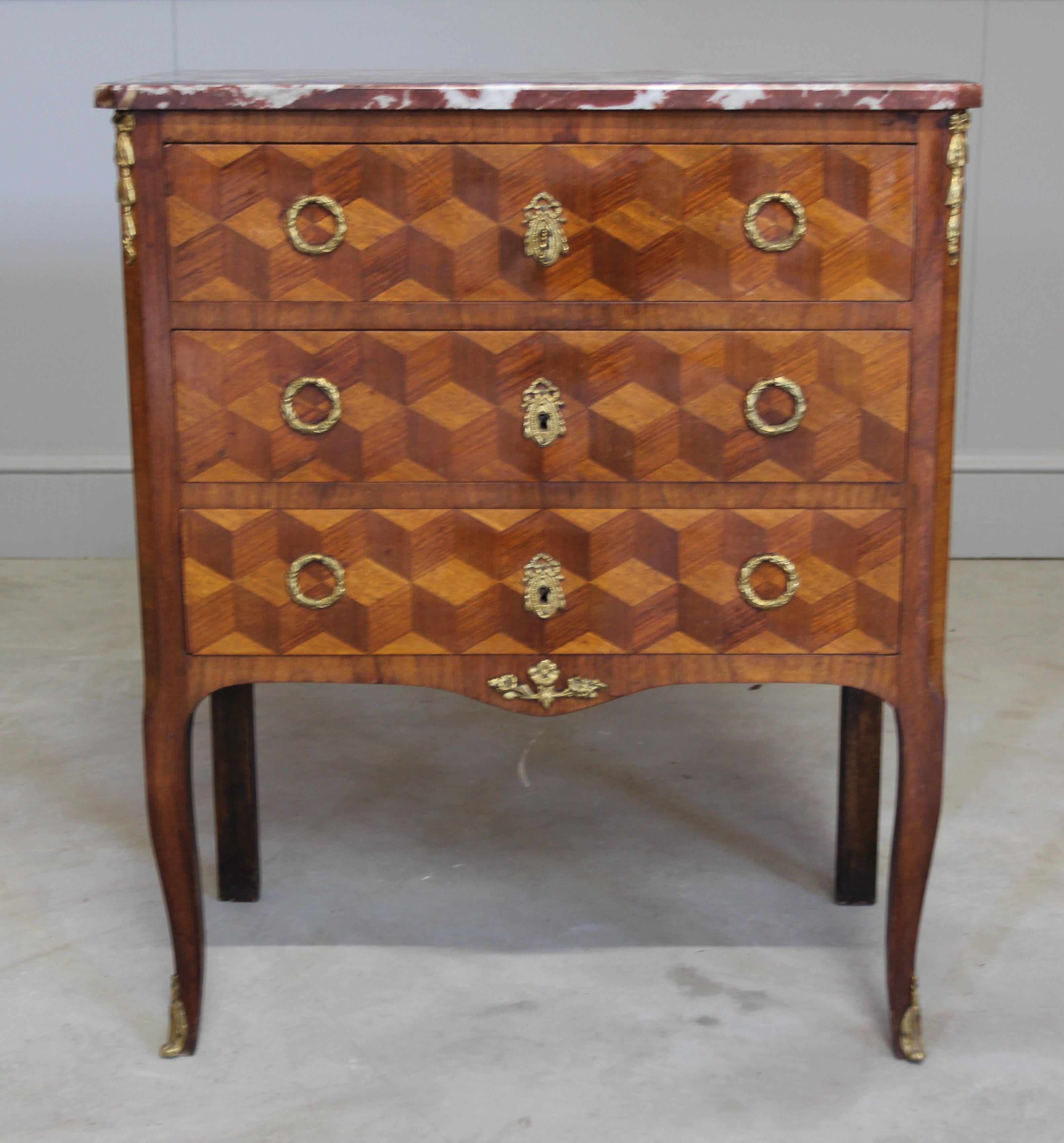 A 19th century French parquetry inlaid chest of drawers of small proportion, the marble top above three long graduated drawers, on scroll legs with ormolu mounts. with a working key. 

Coming from the 19th century this chest of drawers is truly