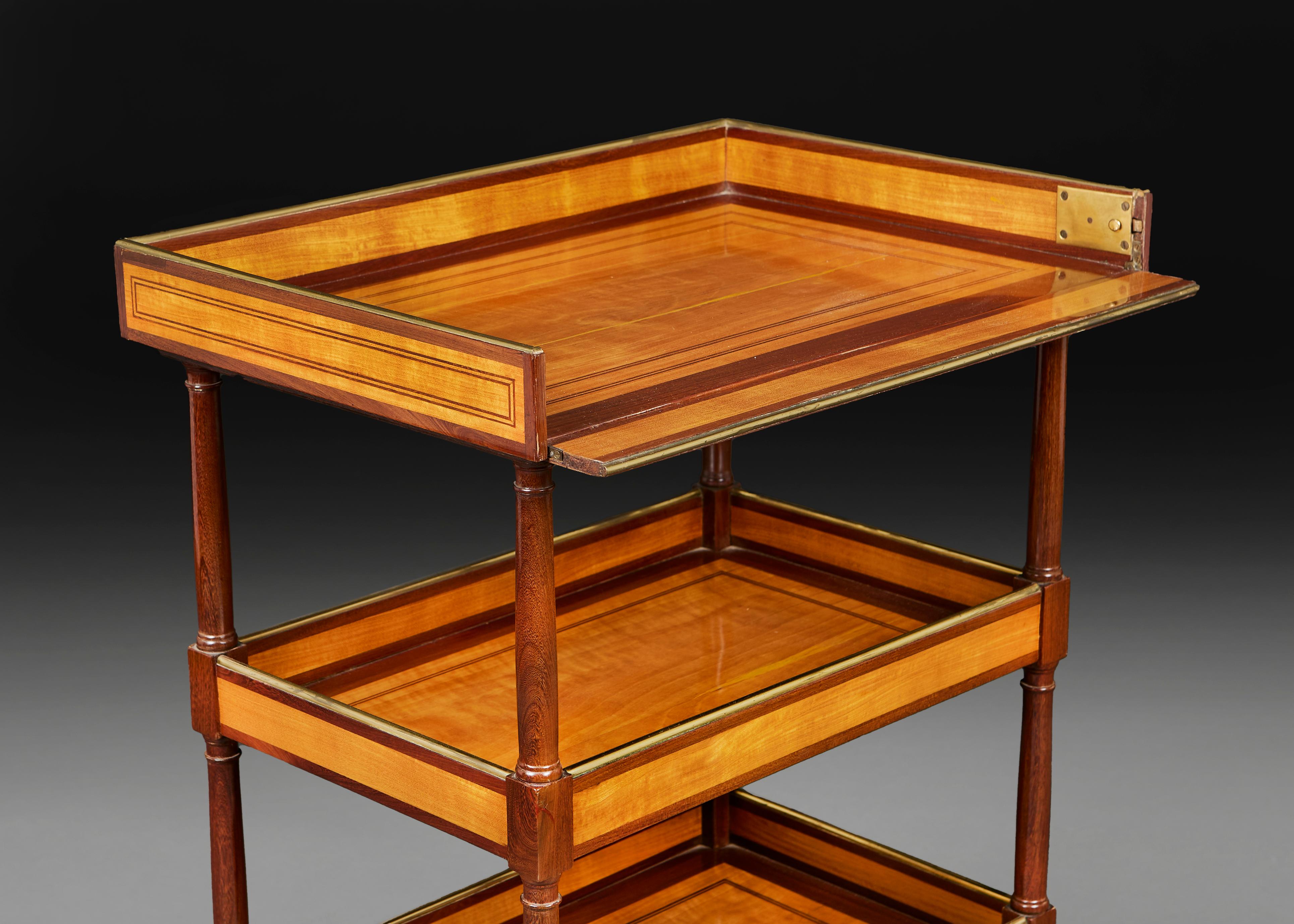 Etagère à trois niveaux en bois satiné du 19e siècle. Réalisé en bois de satin incrusté et garnitures en laiton, avec des roulettes en laiton finissant les pieds, et avec un bouton pour déplier l'étagère supérieure.