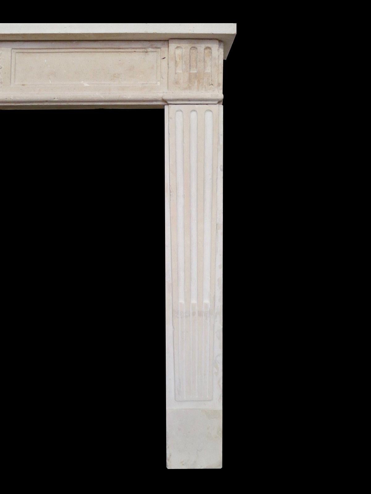 An antique Louis XVI style French stone fireplace, from the 19th century. The stop fluted jambs supporting a fielded carved frieze with a bowl of fruit to centre and conforming end blocks of stop flutes. Simple shelf above. 

Opening size 96cm