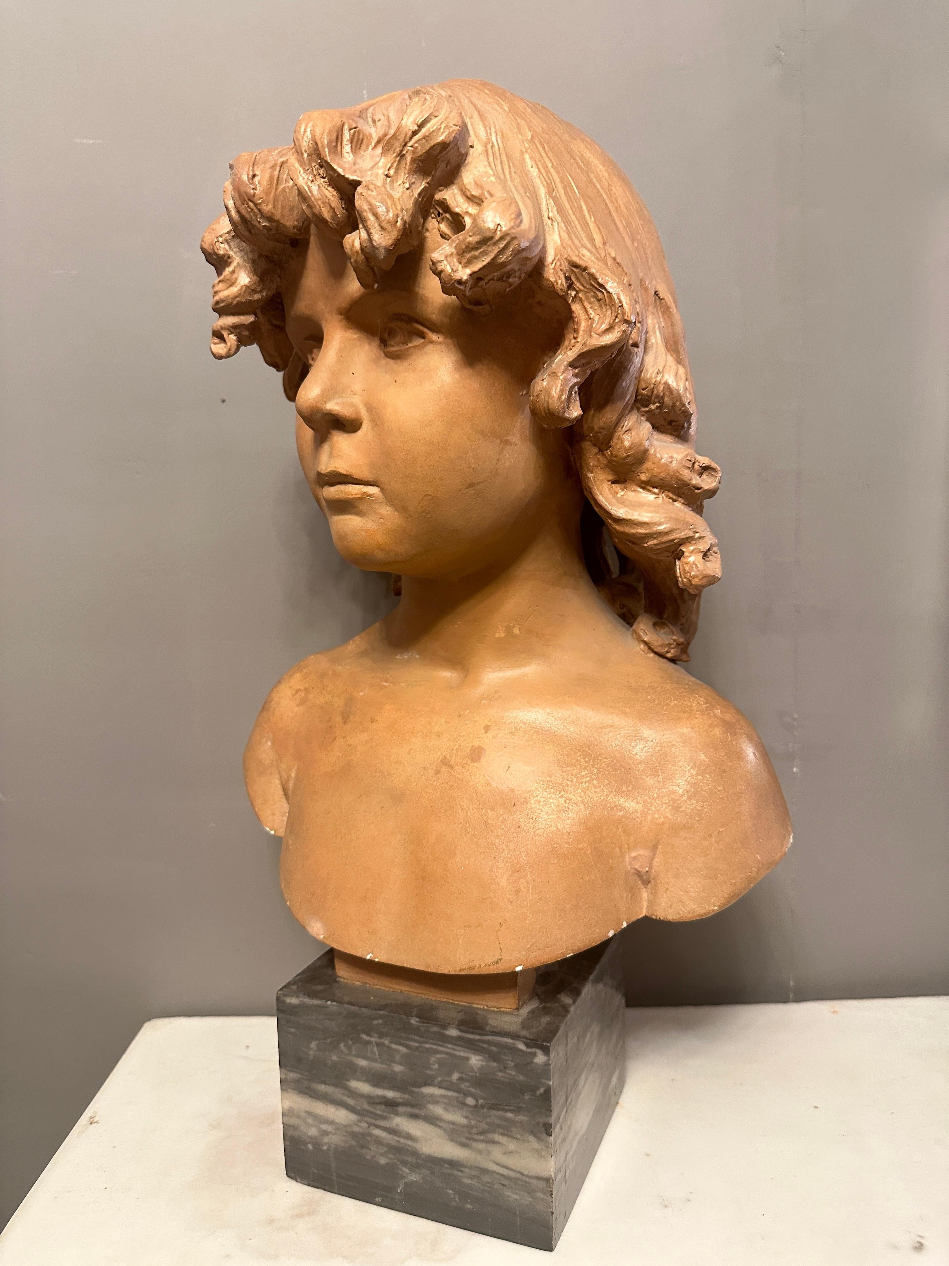 A French Terracotta bust of a young boy stood on an Italian bardiglio marble square soccle. The full head of curly hair cascading over face and shoulders. Original untouched condition, warm and worn patina. French late 19th century 