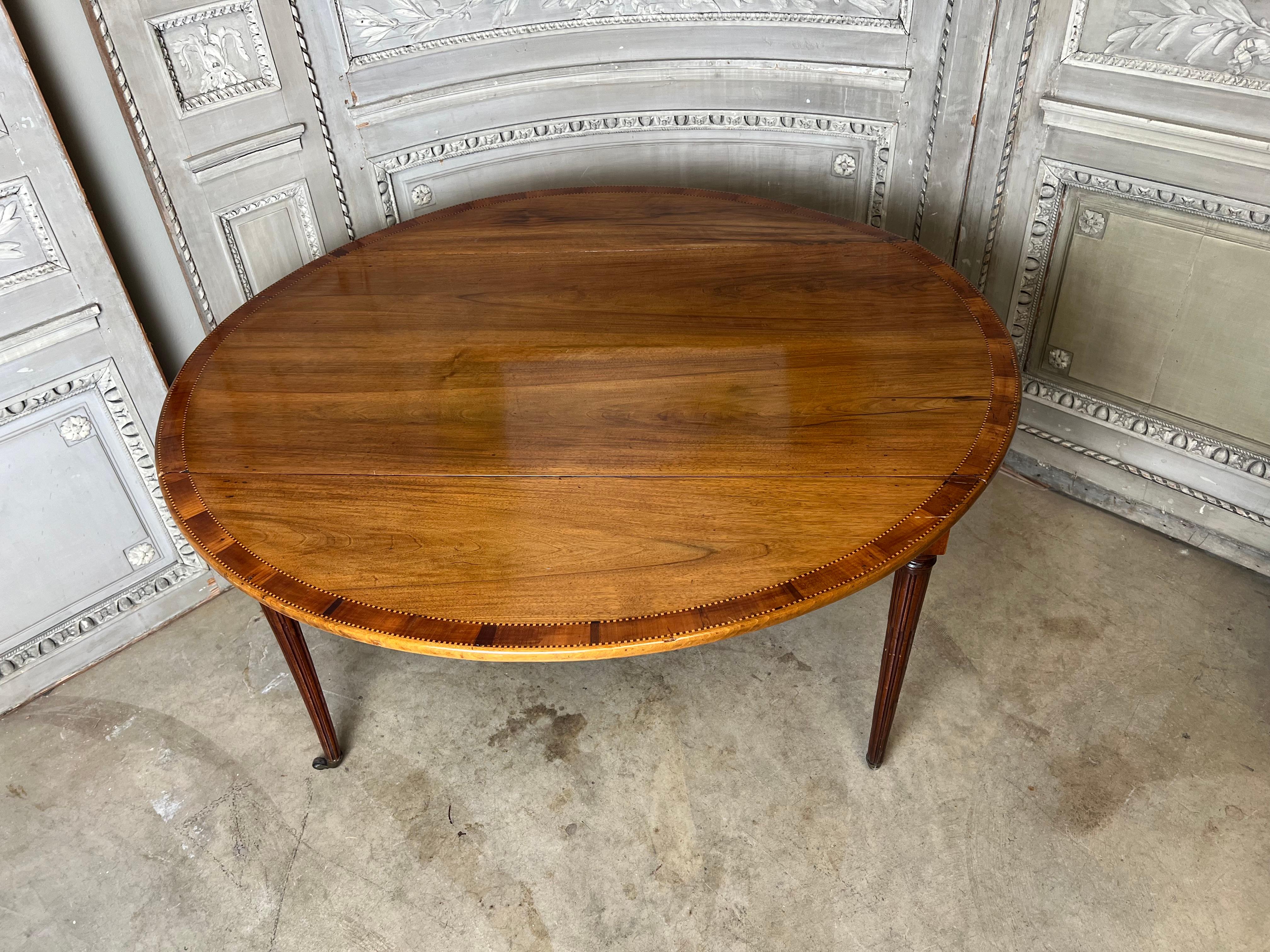 Table de salle à manger en noyer du début du 19e siècle, avec bandes en parquet d'acajou et pieds ronds cannelés.  Cette table polyvalente était autrefois une table de salle à manger à rallonge qui a été fermée il y a longtemps et transformée en une