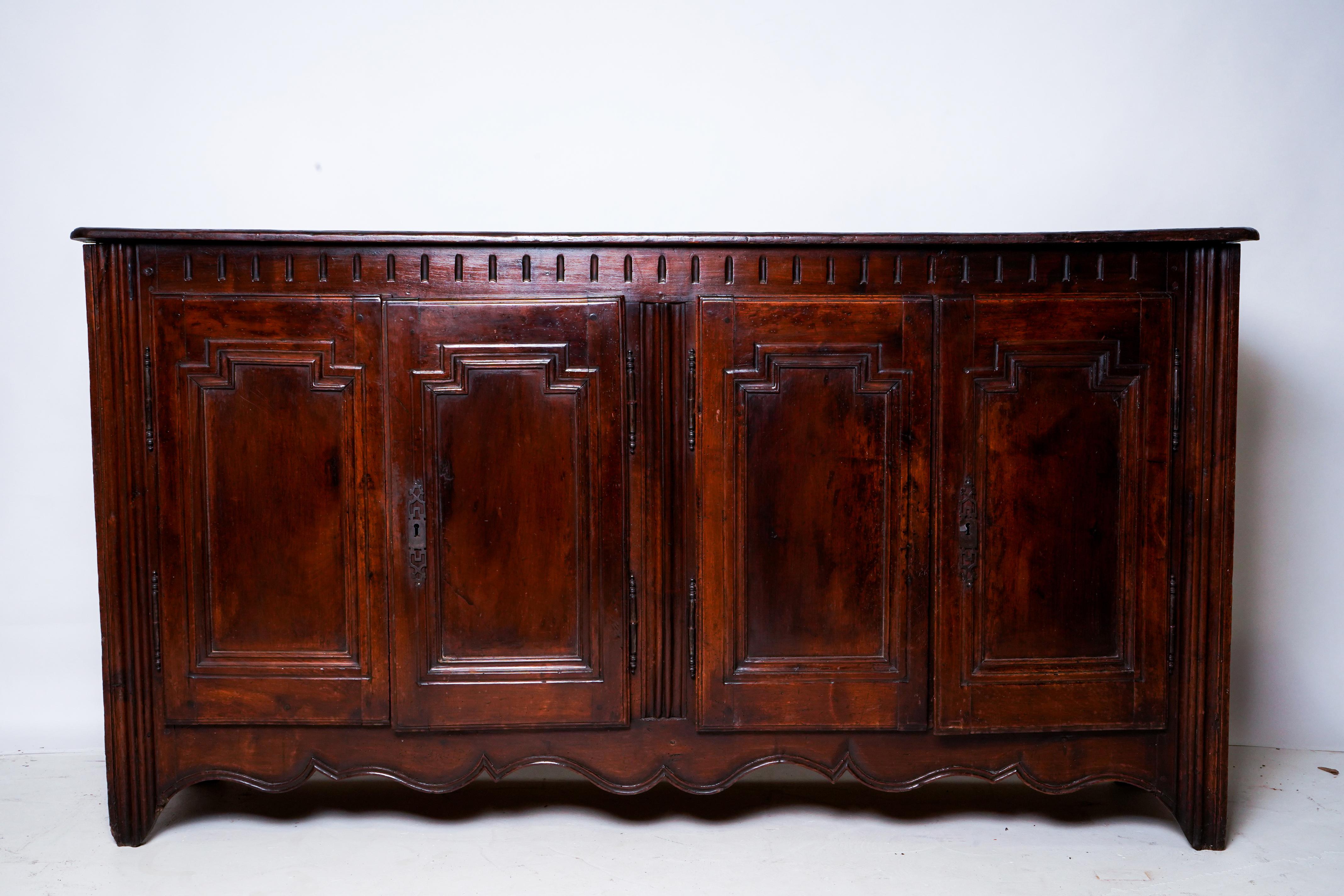 This boldly understated sideboard is made from Walnut Wood and features a unique combination of rectilinear and curvilinear  decoration. It is from the Dordogne region of France and has been preserved in its unrestored state.
