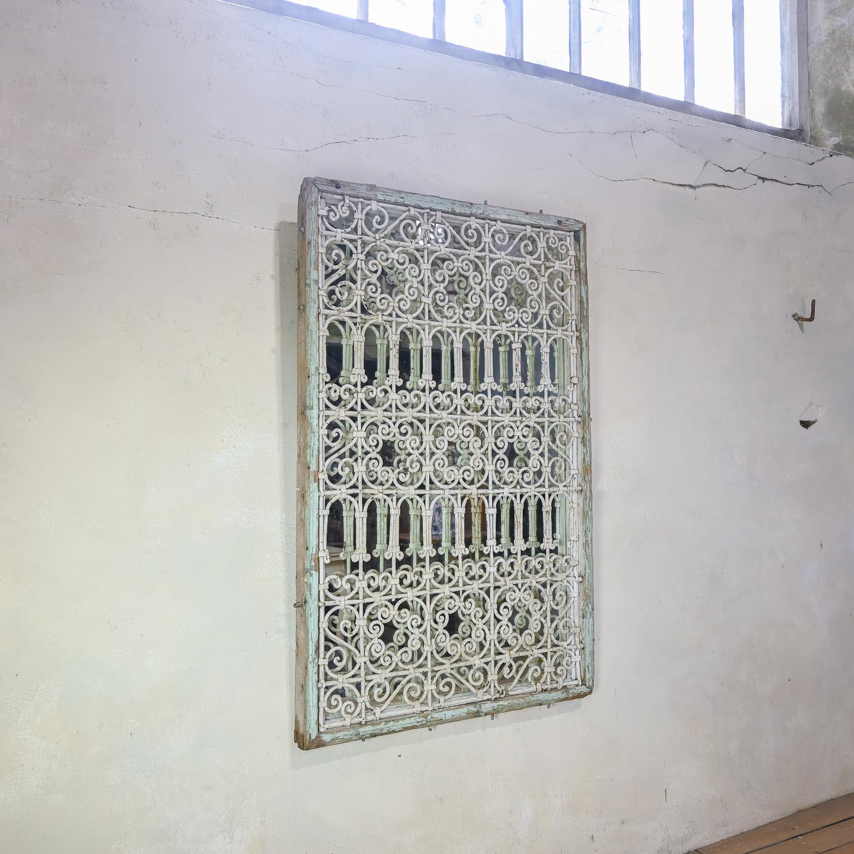 Un elegante specchio francese in ferro battuto risalente agli inizi del XX secolo. Incorpora un'inferriata in ferro battuto a volute del XIX secolo - incorniciata in modo semplice, con la sua vernice originale verde chiaro. Si presta bene a una
