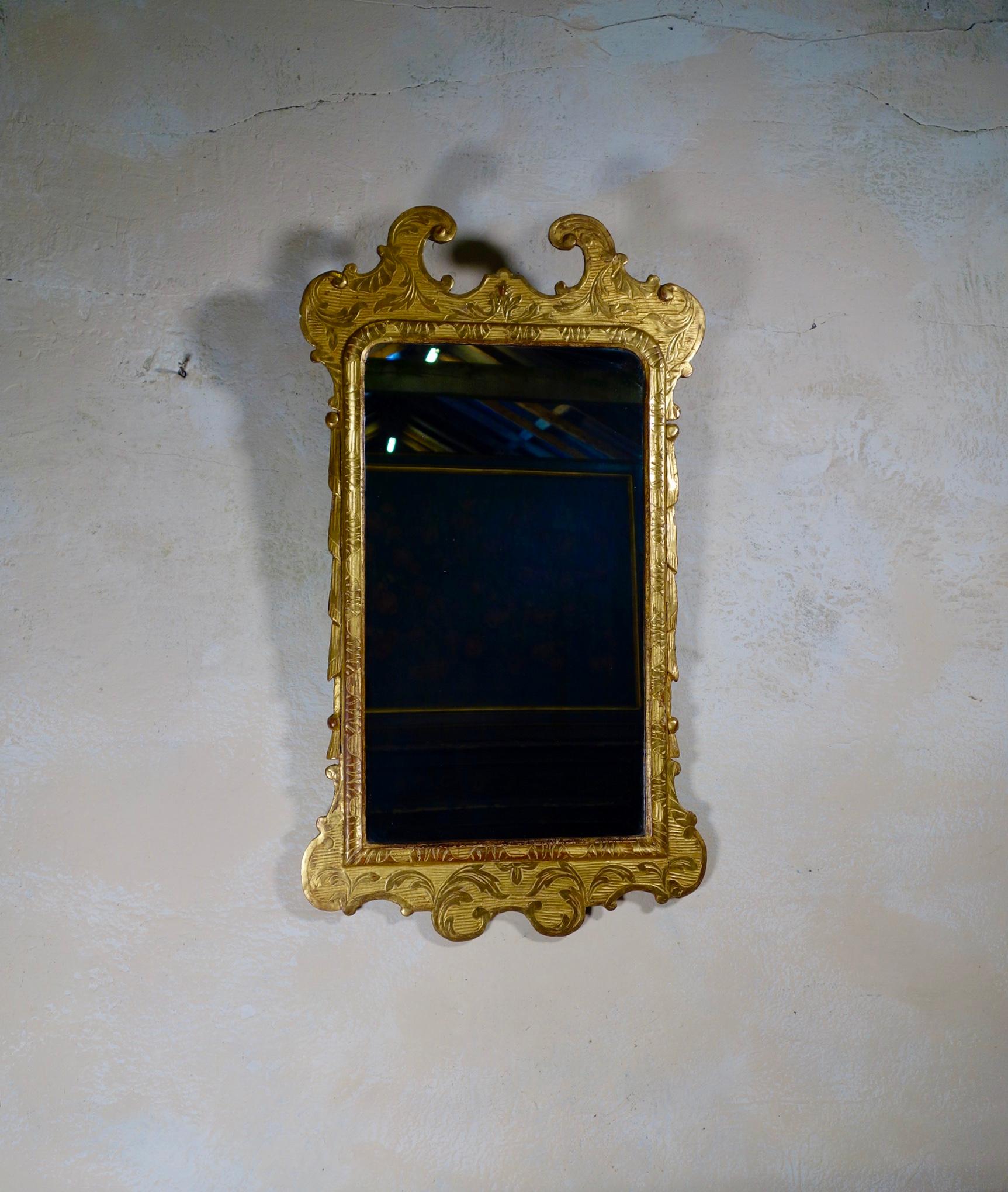 A George I style gesso wall mirror dating from the 19th century. Featuring a rich two-tone gilding which adds a great sense of depth to the framework of the mirror. This mirror demonstrates stylized foliage and scrollwork with shaped scrolling