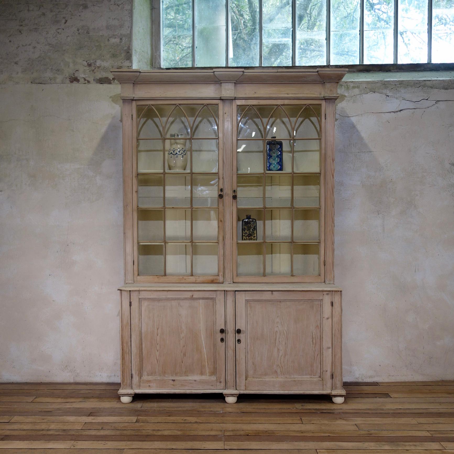 A striking large scale Gothic Revival cabinet/bookcase, dating from the mid 19th century. Demonstrating a pair of upper astral glazed doors above a pair of paneled doors. The upper shelves are supported by adjustable supports providing a multitude