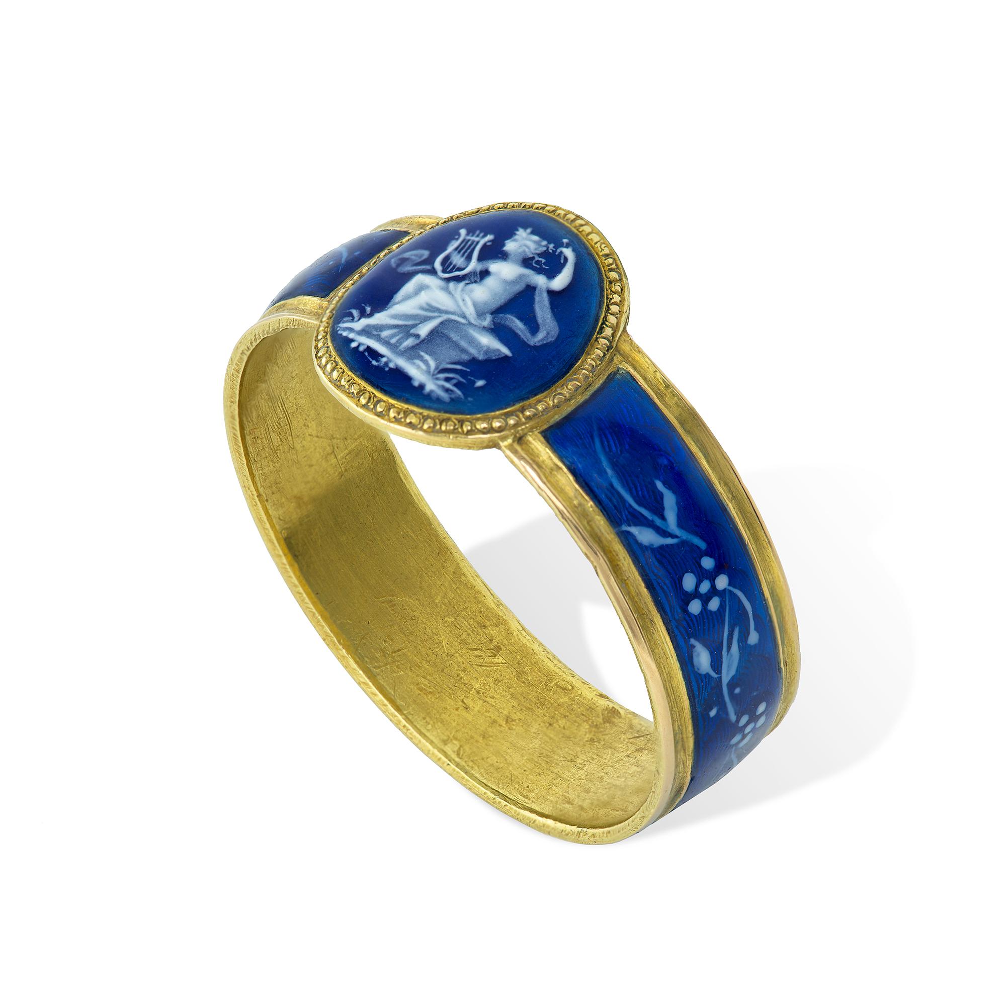 A 19th century grisaille enamel ring, the blue and white enamel oval panel centre, painted in cameo style, depicting Erato, the Muse of Lyric poetry playing the lyre, to a blue background, surrounded by a gold beaded border, all to a blue guilloché