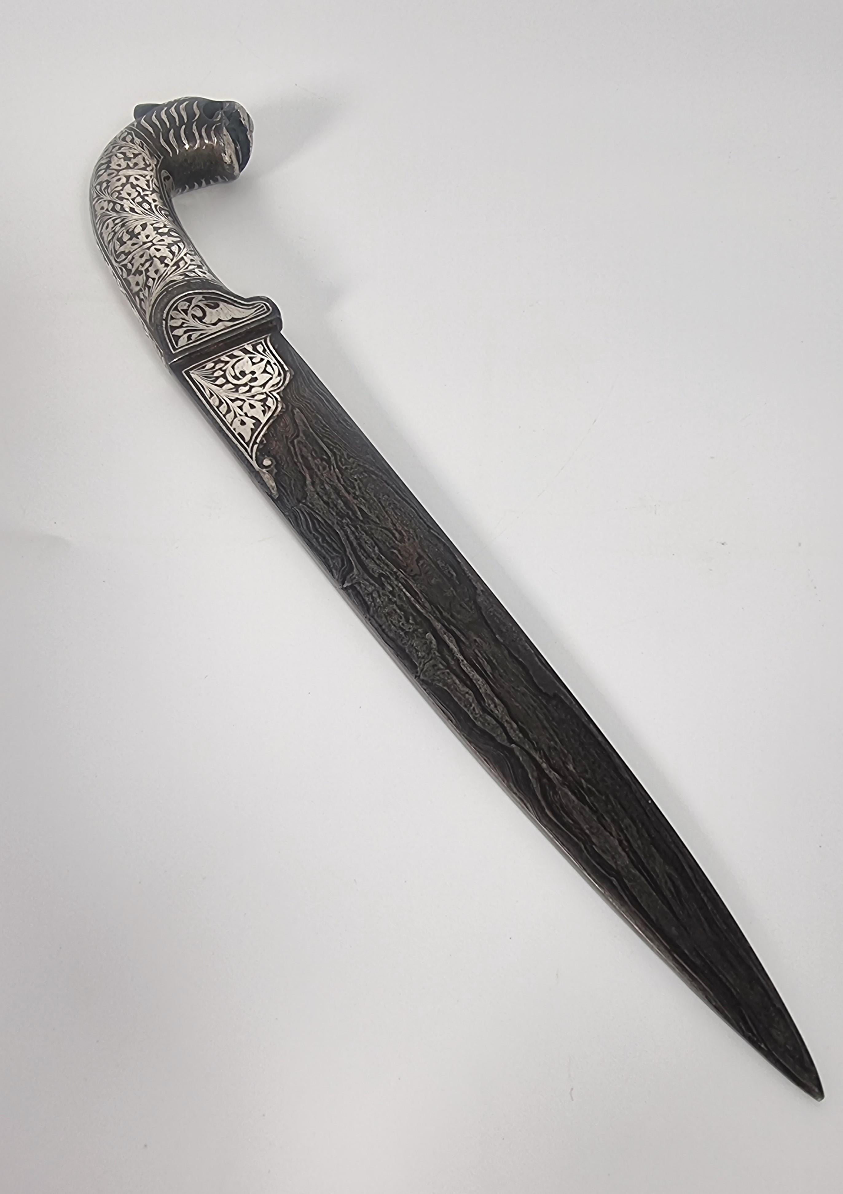 Ein feiner, verzierter indischer Dolch aus dem 19. Jahrhundert, der aus handgeschmiedetem, gefaltetem Stahl, dem so genannten Damast, hergestellt wurde, der auf der Klinge ein fast holzähnliches Muster aufweist.

Das gesamte Messer ist aus massivem