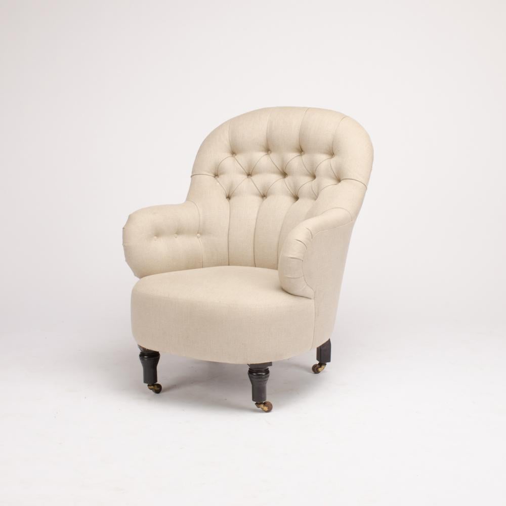 A restored 19th century Irish library armchair having a tufted upholstered back resting on four legs terminating in casters.