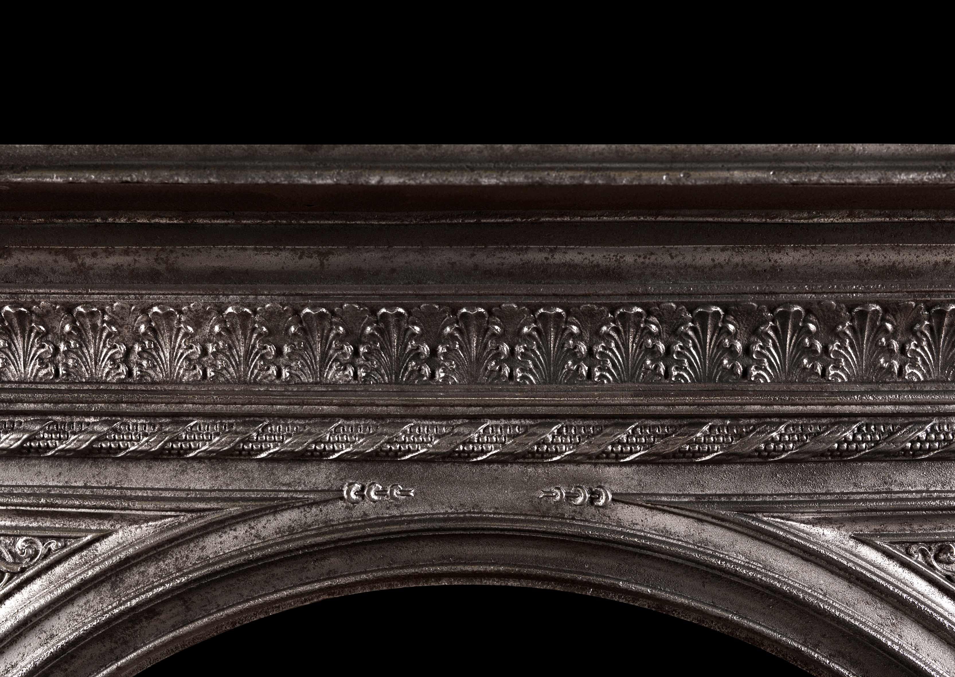 Une jolie cheminée en fonte anglaise du milieu du 19ème siècle. La frise est ornée de feuilles d'acanthe, les montants sont ornés de consoles à volutes et de moulures en corde sur les bords intérieurs et extérieurs. L'ouverture en arc avec des