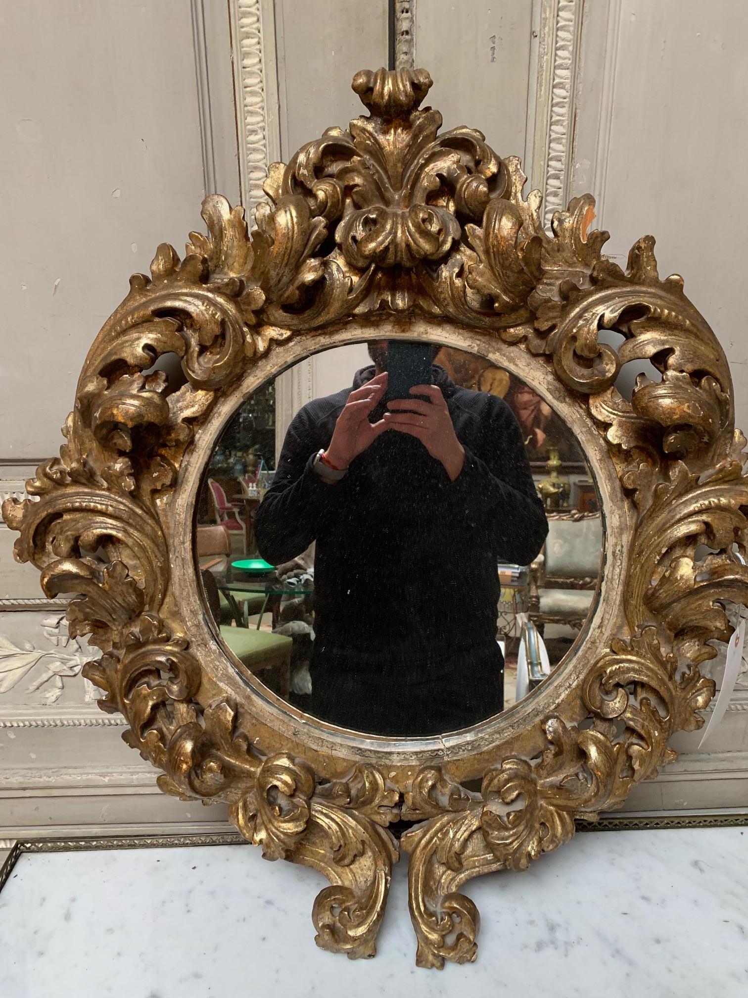 This gorgeous 19th century Italian carved and giltwood mirror is decorated with an elaborate Baroque scroll work. It's scale makes for a beautiful accent around your house and it's perfect for a powder room. The mirror shows a lovely patina