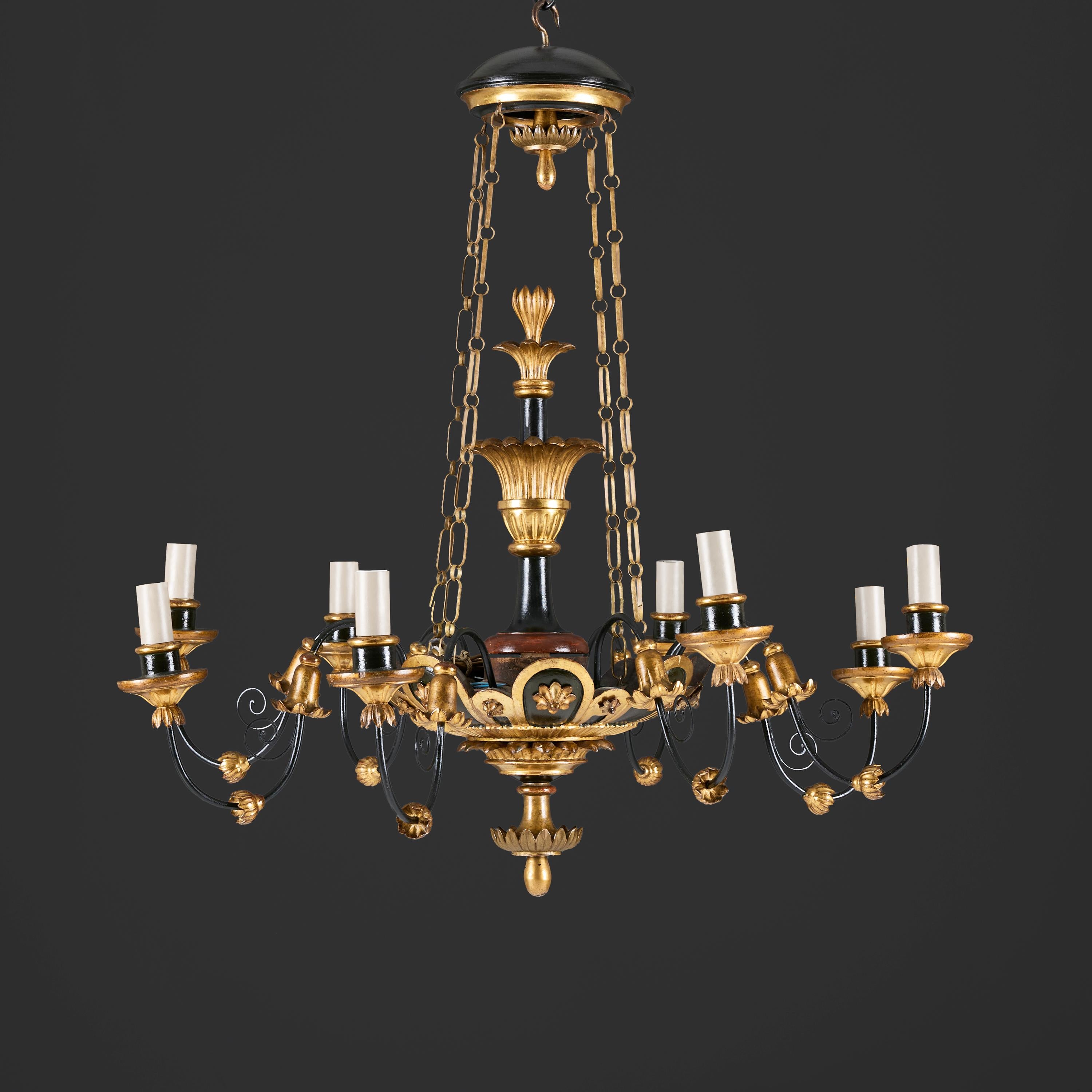 Italie, vers 1820

Lustre italien du début du XIXe siècle en bois ébonisé et doré, à huit bras, finement sculpté d'ornements néoclassiques ou de feuilles d'acanthe stylisées et d'un fleuron en forme de gland inversé, soutenu par trois chaînes dorées