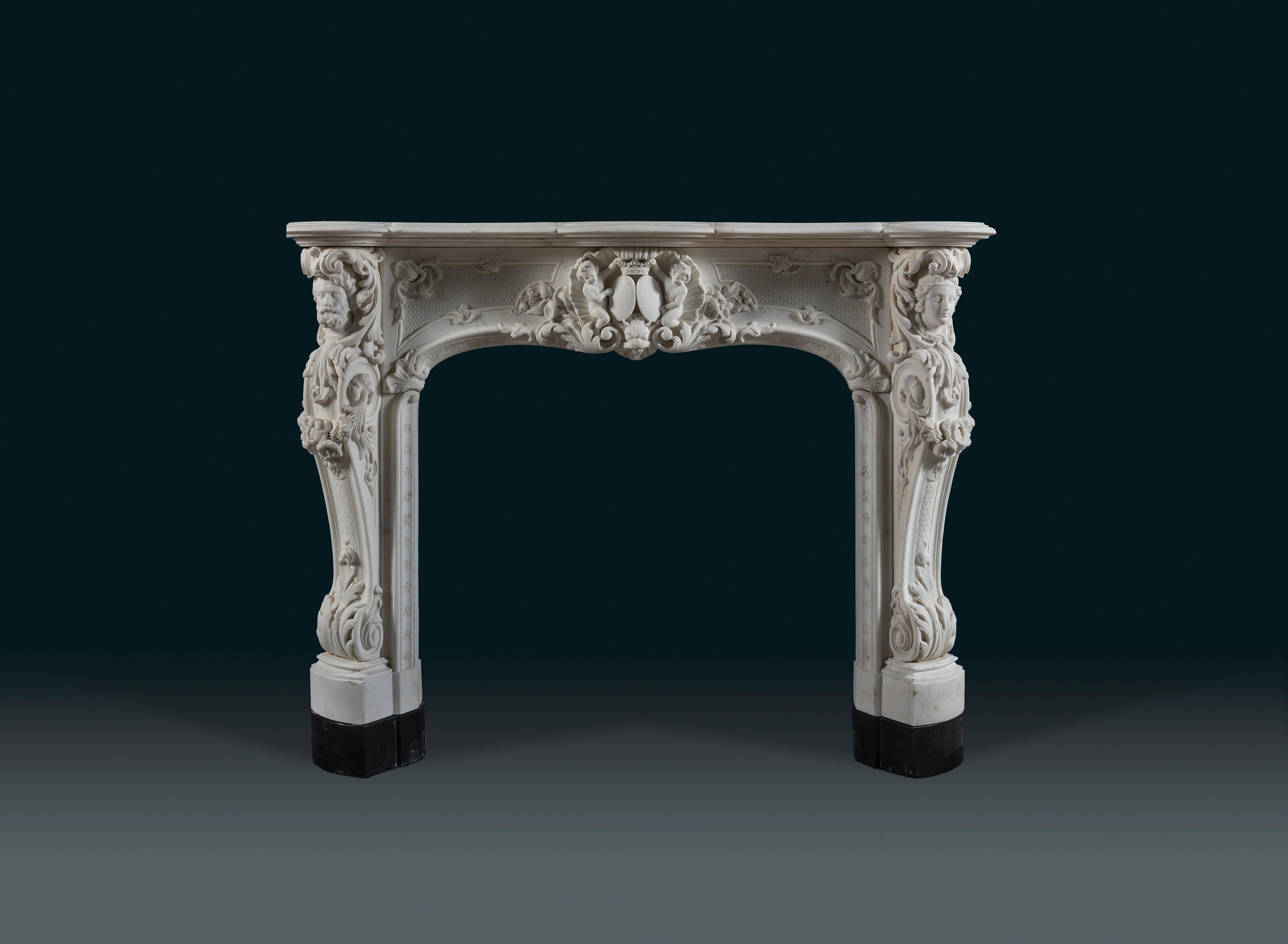 A 19th century, Louis XV style Statuary marble rococo chimneypiece. Each canted jamb is festooned with carved foliage ranging from great curls of acanthus to prim flowers. It is likely this chimneypiece is a celebration of conjugal love and unity,