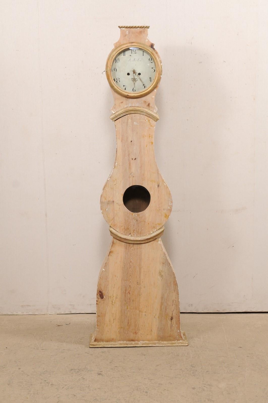 A Swedish wood carved Mora floor clock from the 19th century. This antique Mora clock from Sweden features a raised and flattened top bonnet, trimmed in rope-carved trim adorning it's head, a raindrop-shaped door and belly, rounded-triangular lower