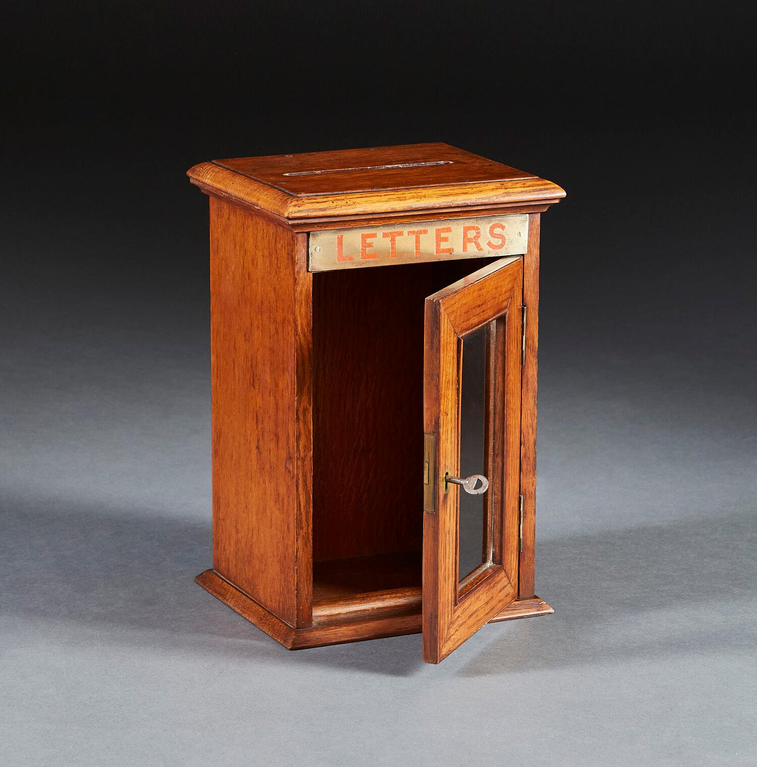 A mid nineteenth century oak table top letter box with brass sign to the front, opening with a locked window, with a slot to the top.

Provenance: From the Bishop of Norwich’s residence.