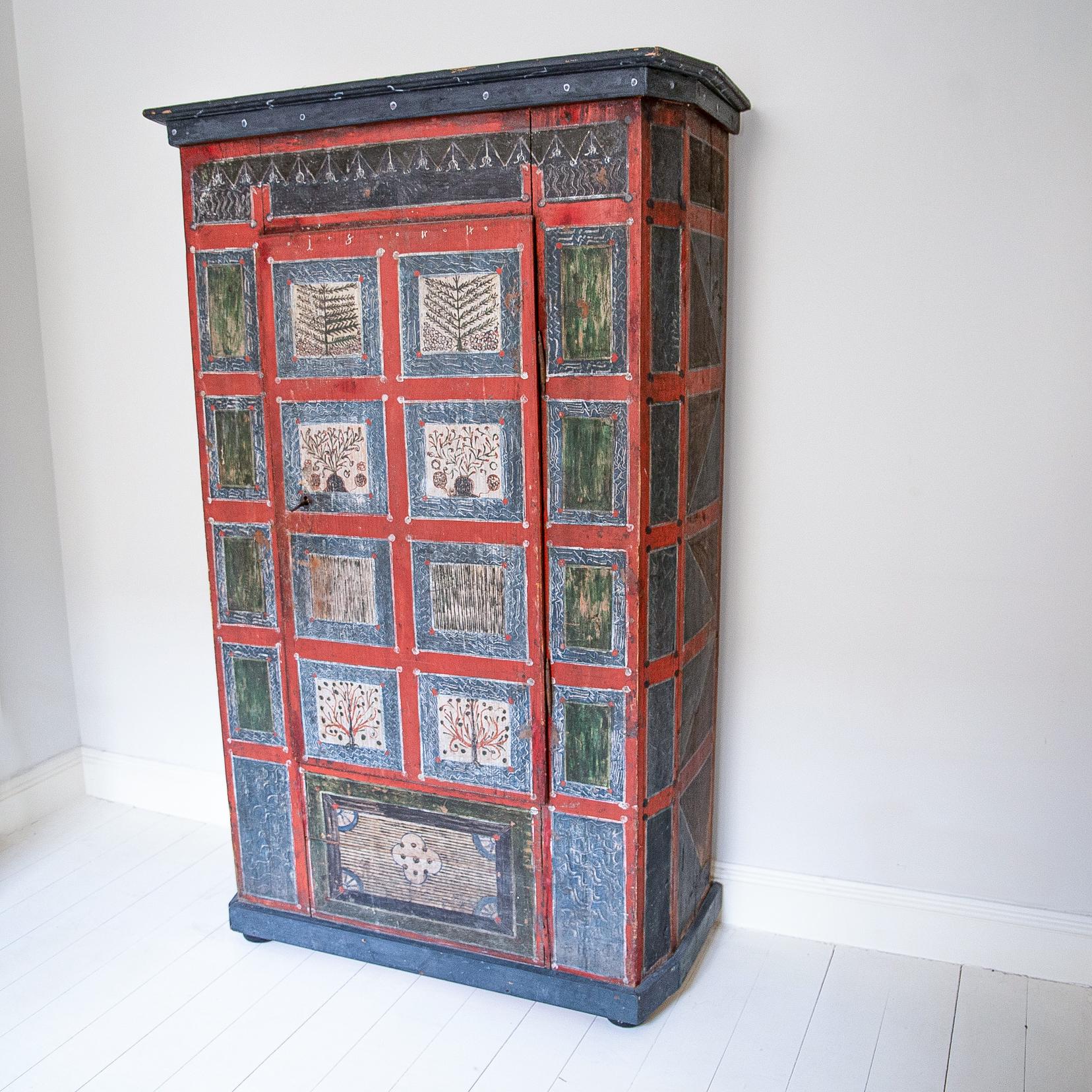 A wonderfully characterful and decorative armoire in the bohemian taste with superb aged powdered colouration and patina. With uniquely Ukranian hand brushed illustrative work showing stylised motifs of fir trees and flowering specimens all framed