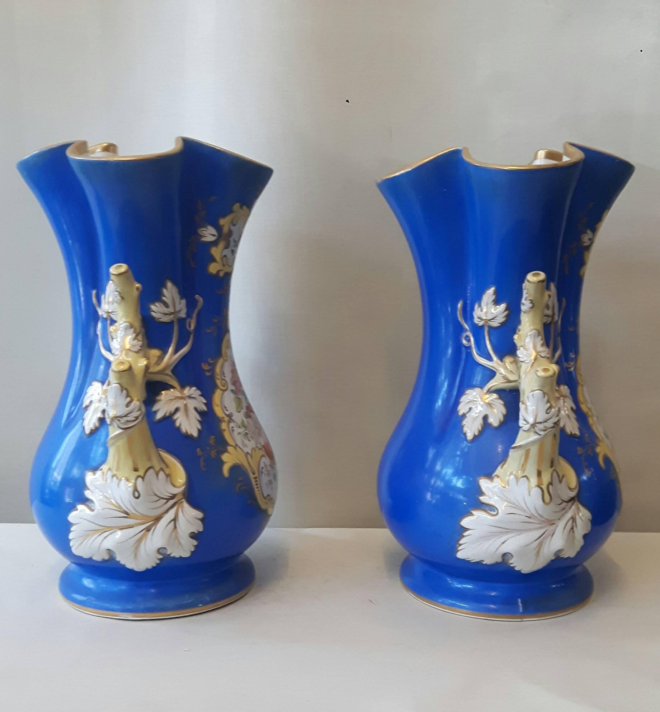 A decorative pair of Ridgway vases, hand-painted with central flower panels and elegantly painted and gilded handles.
